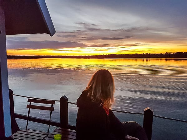 Eine Frau auf einem Floß blickt auf den Sonnenuntergang.