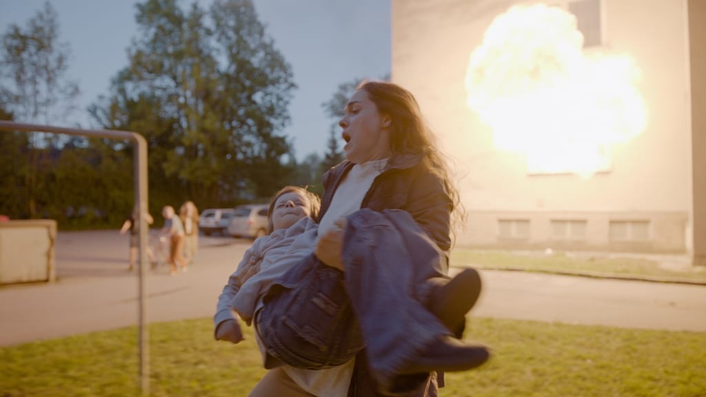 Frau trägt ein Kind weg. Im Hintergrund eine Explosion an einem Gebäude. Parkplatz mit Autos und Bäumen. Dramatische Stimmung.