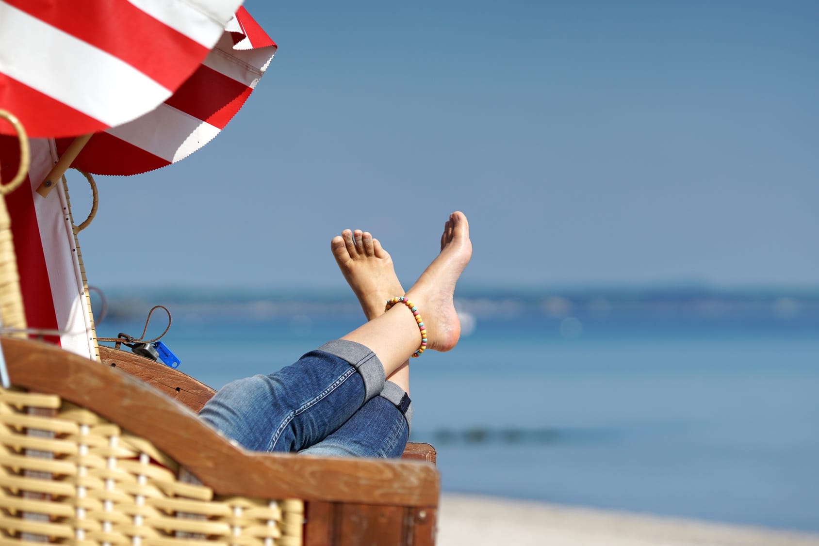 Füße ragen aus dem Strandkorb, Meer im Hintergrund.