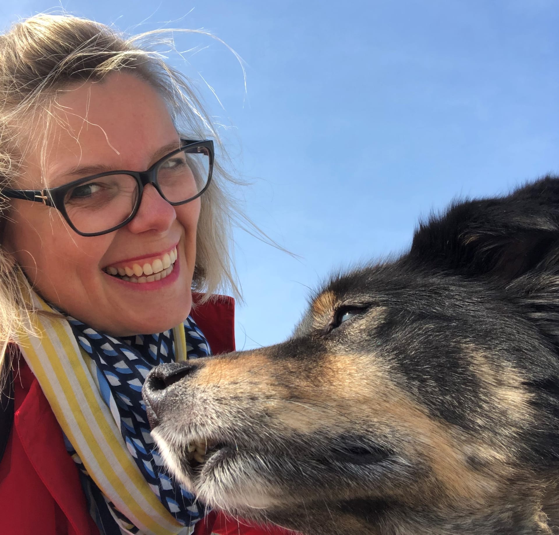 Frau mit Hund, sie lächelt, er schaut in die Ferne.