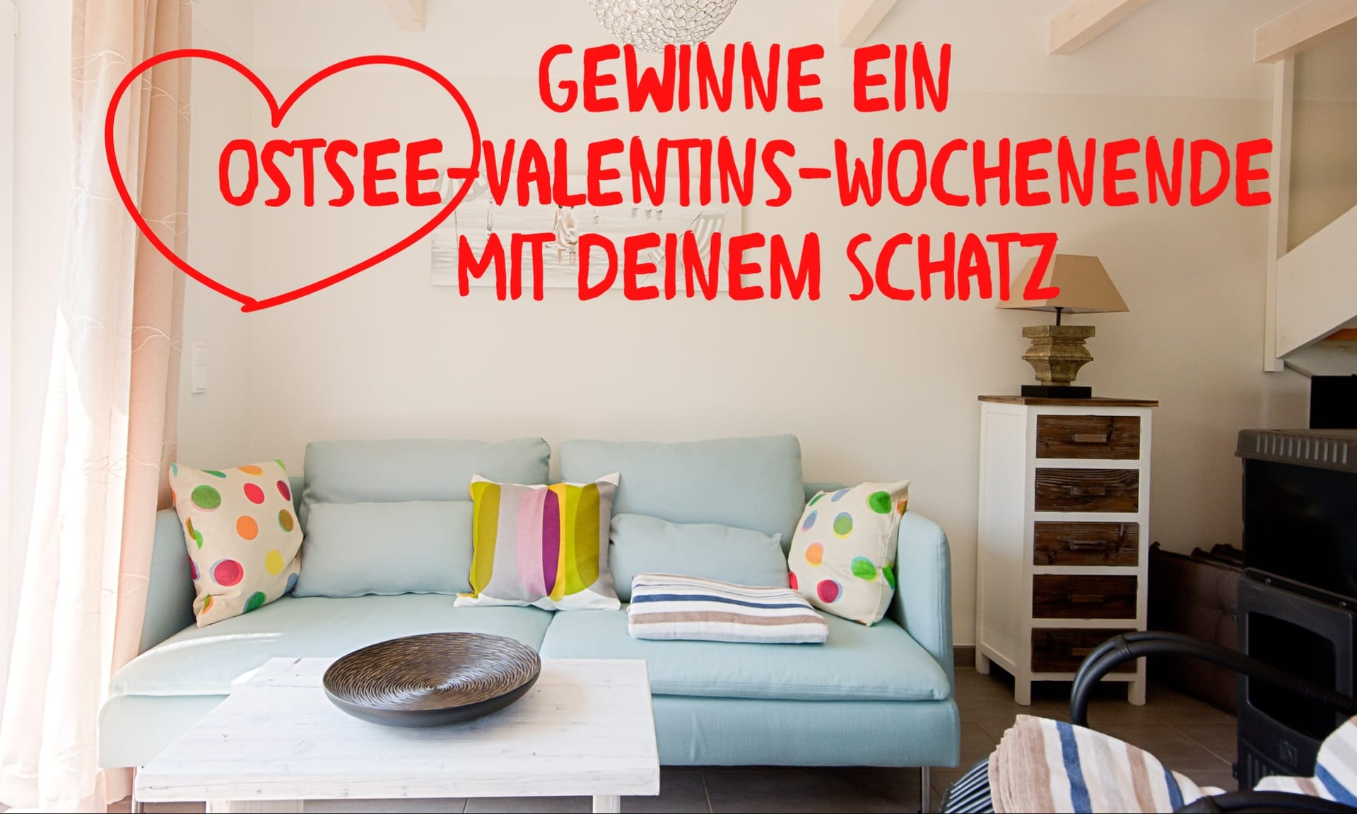 Wohnzimmer mit hellblauem Sofa und darüber eine Grafik mit der Aufschrift: Gewinne deine Ostsee-Valentins-Wochenende mit deinem Schatz.