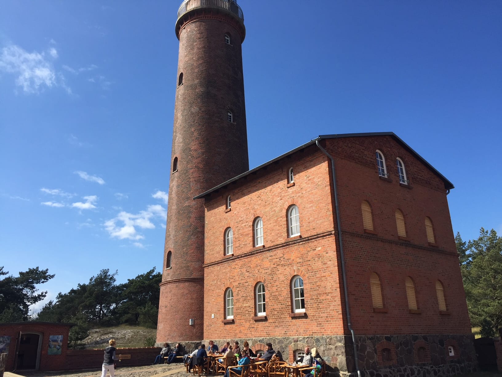 Roter Backstein-Leuchtturm auf dem Darßer Ort. Das Bauwerk steht unter einem blauen Himmel mit einigen Wolken.