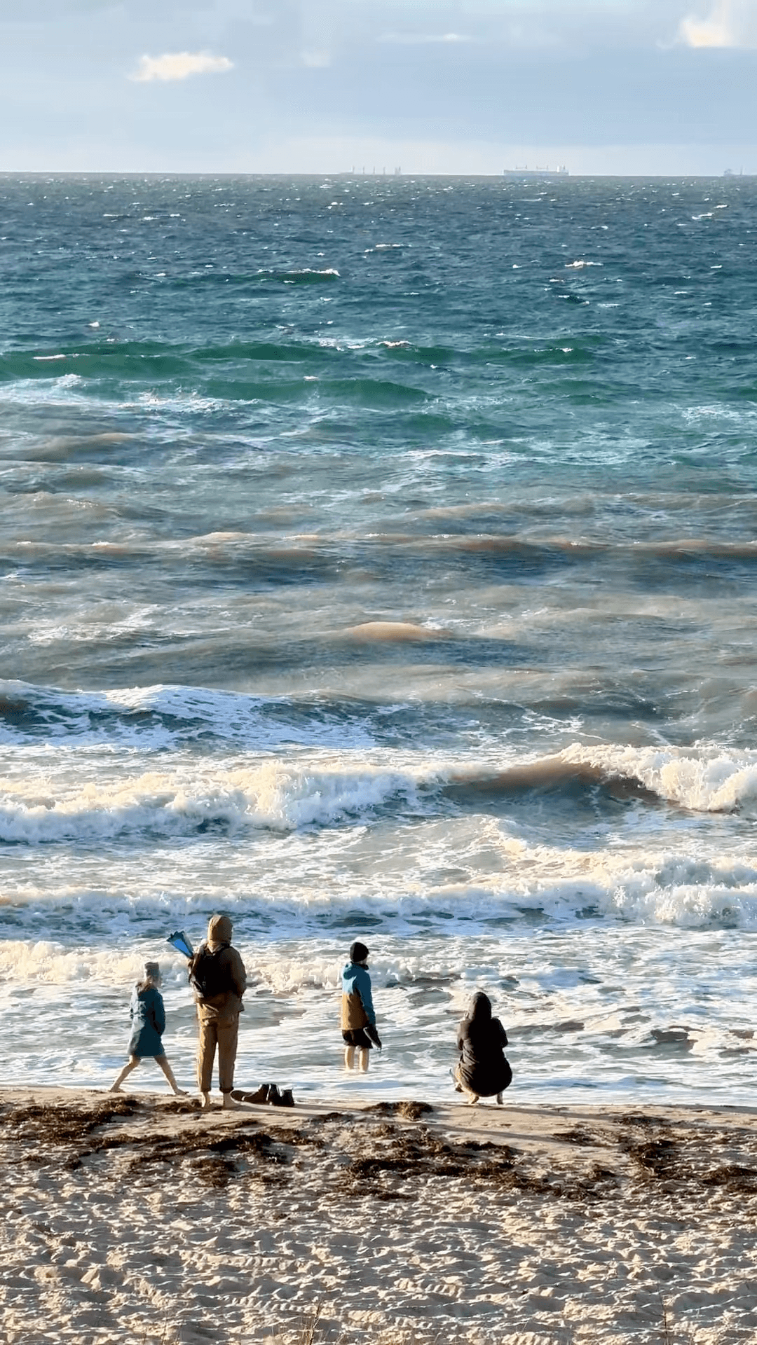 Familie steht am Wasser und guckt auf das Meer