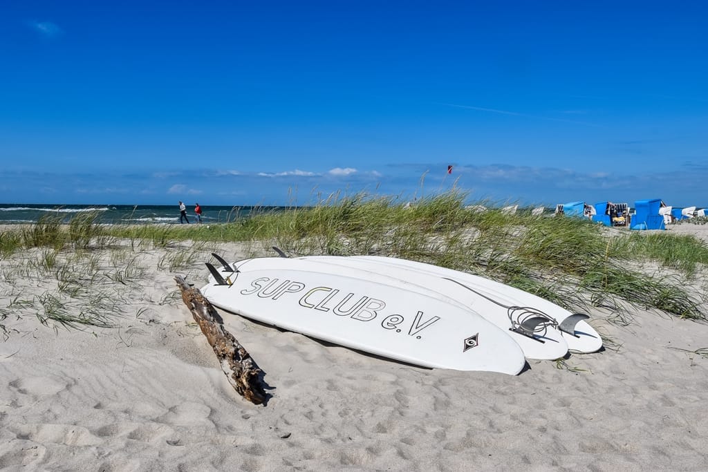 Drei SUP-Boards liegen am Strand.