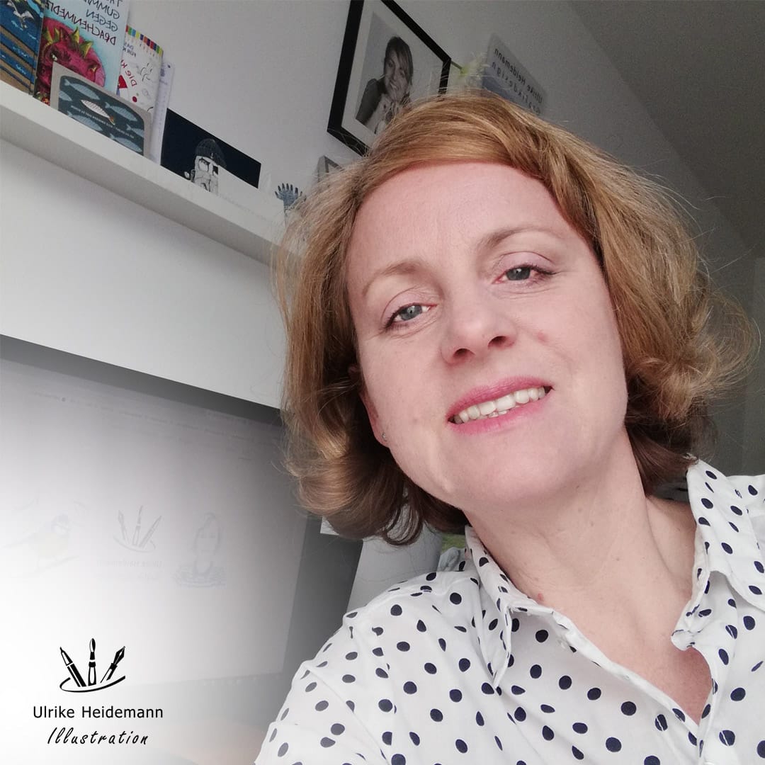 Eine lächelnde Frau in einer gepunkteten Bluse vor einem Regal mit Büchern und Bildern.