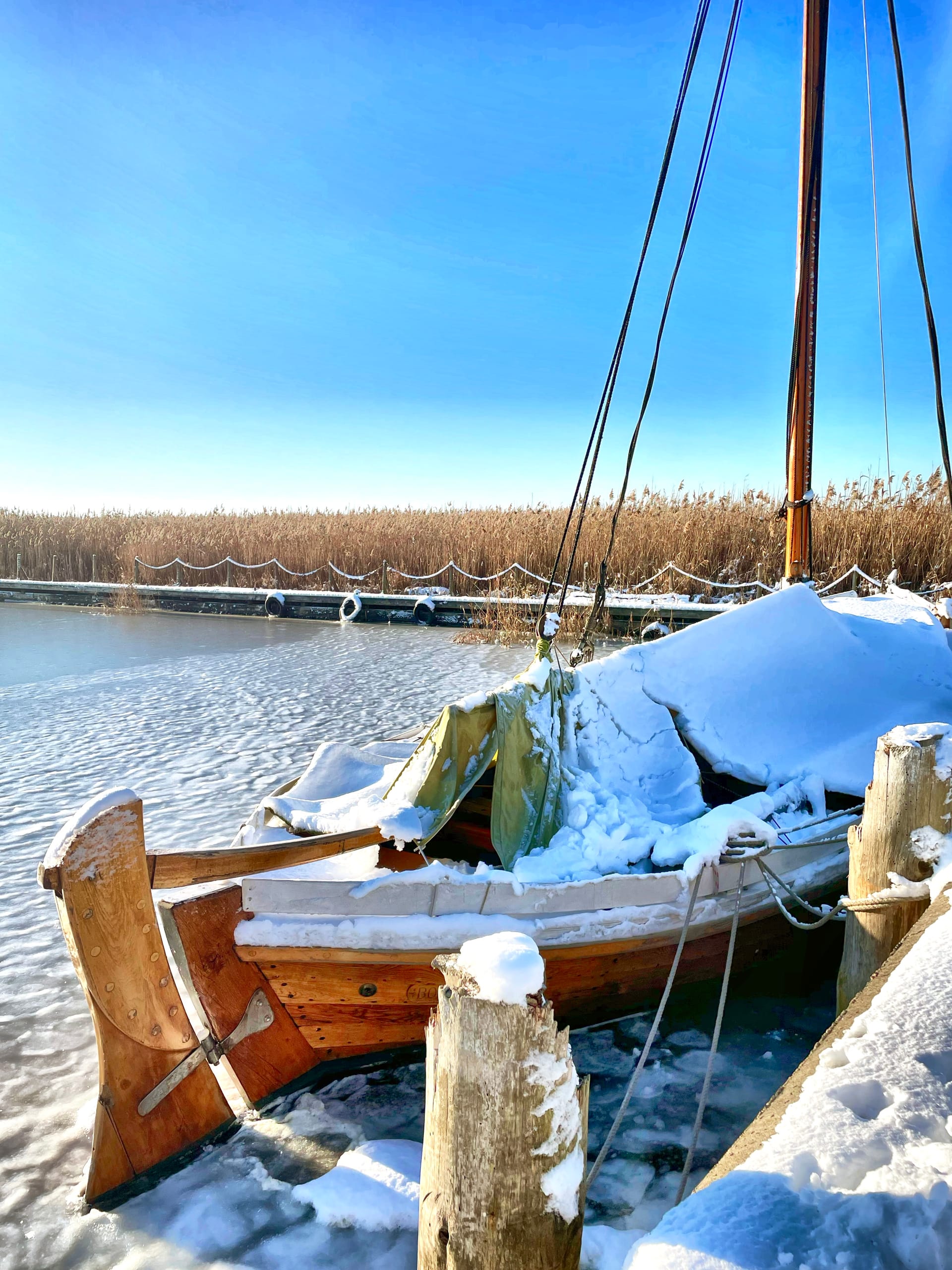 Vereistes Holzboot im winterlichen Hafen, bedeckt mit Schnee und Eis