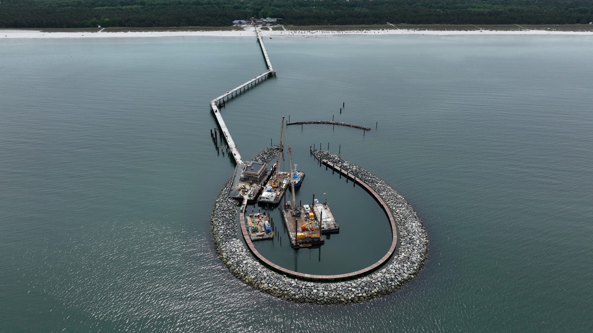 Luftaufnahme der Seebrücke Prerow mit Bauarbeiten und rundem Wellenbrecher in der Ostsee.