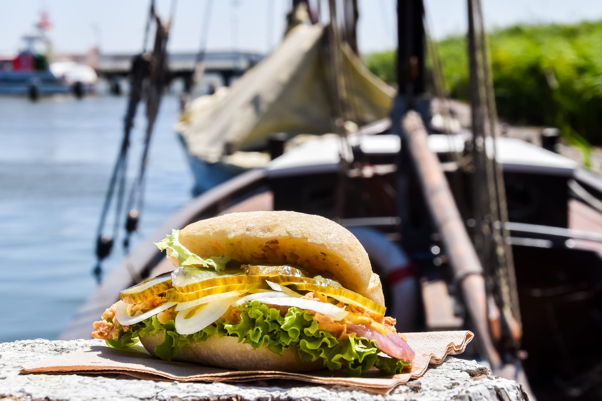 Frisches Fischbrötchen mit Salat vor Zeesenboot im Hafen