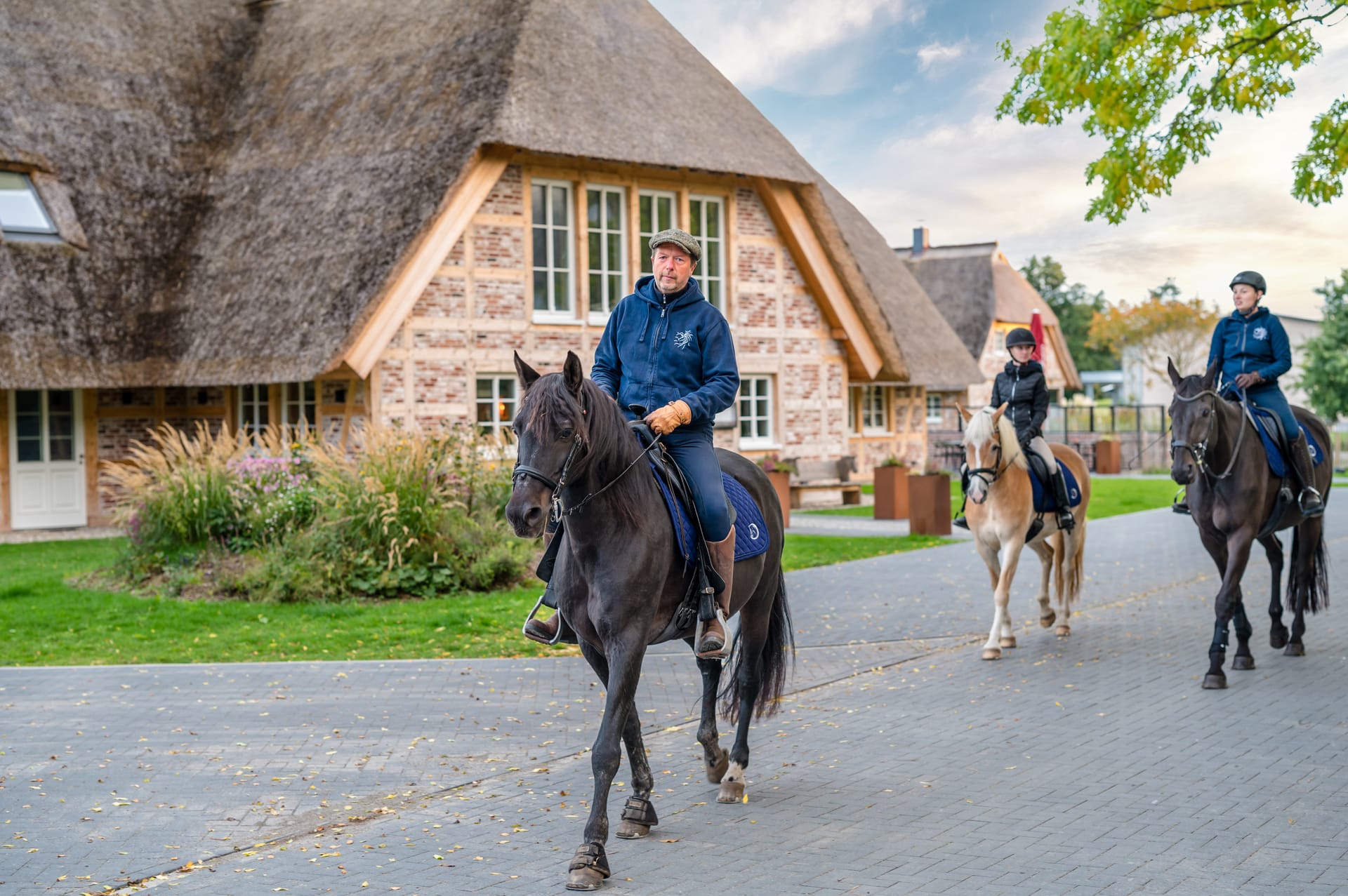 Reitergruppe vor reetgedecktem Gutshaus in Dierhagen