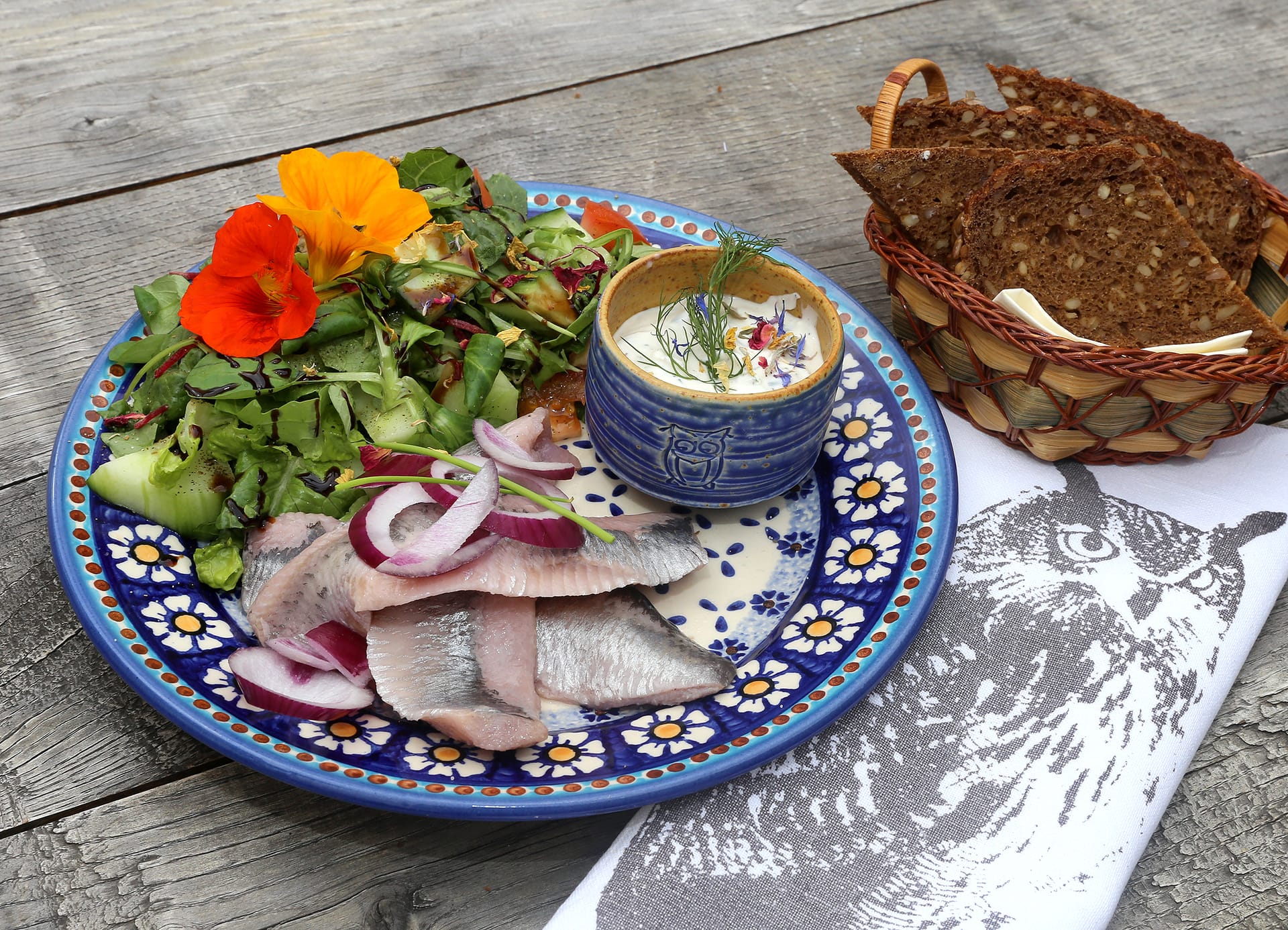 Matjes mit Salat, Kräuterquark und Brot auf rustikalem Tisch