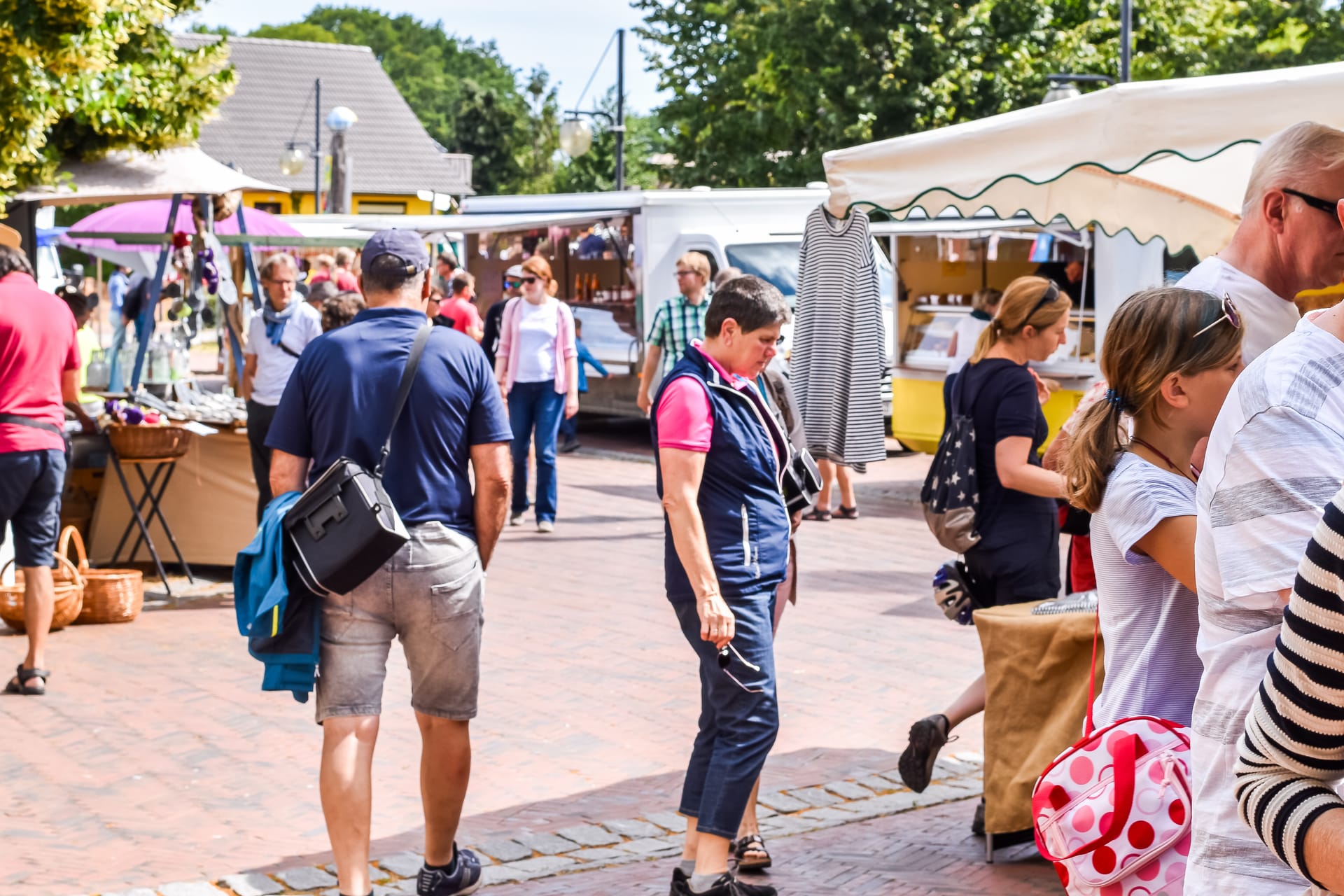 Besucher bummeln über einen belebten Wochenmarkt mit Ständen