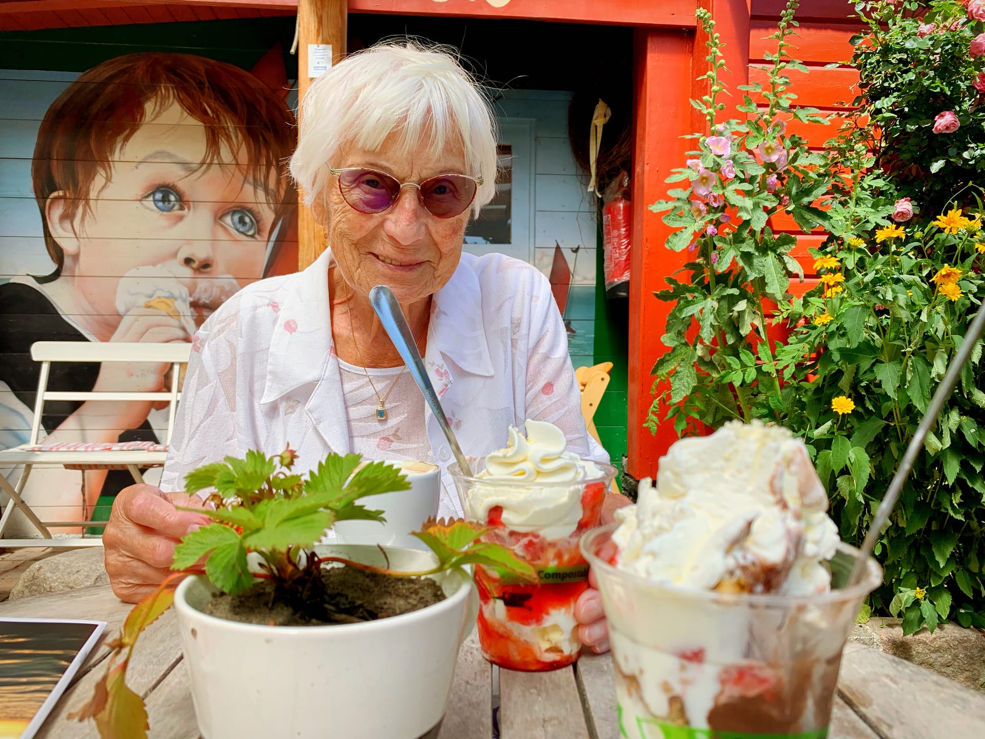 Seniorin genießt Eisbecher im Gartencafé