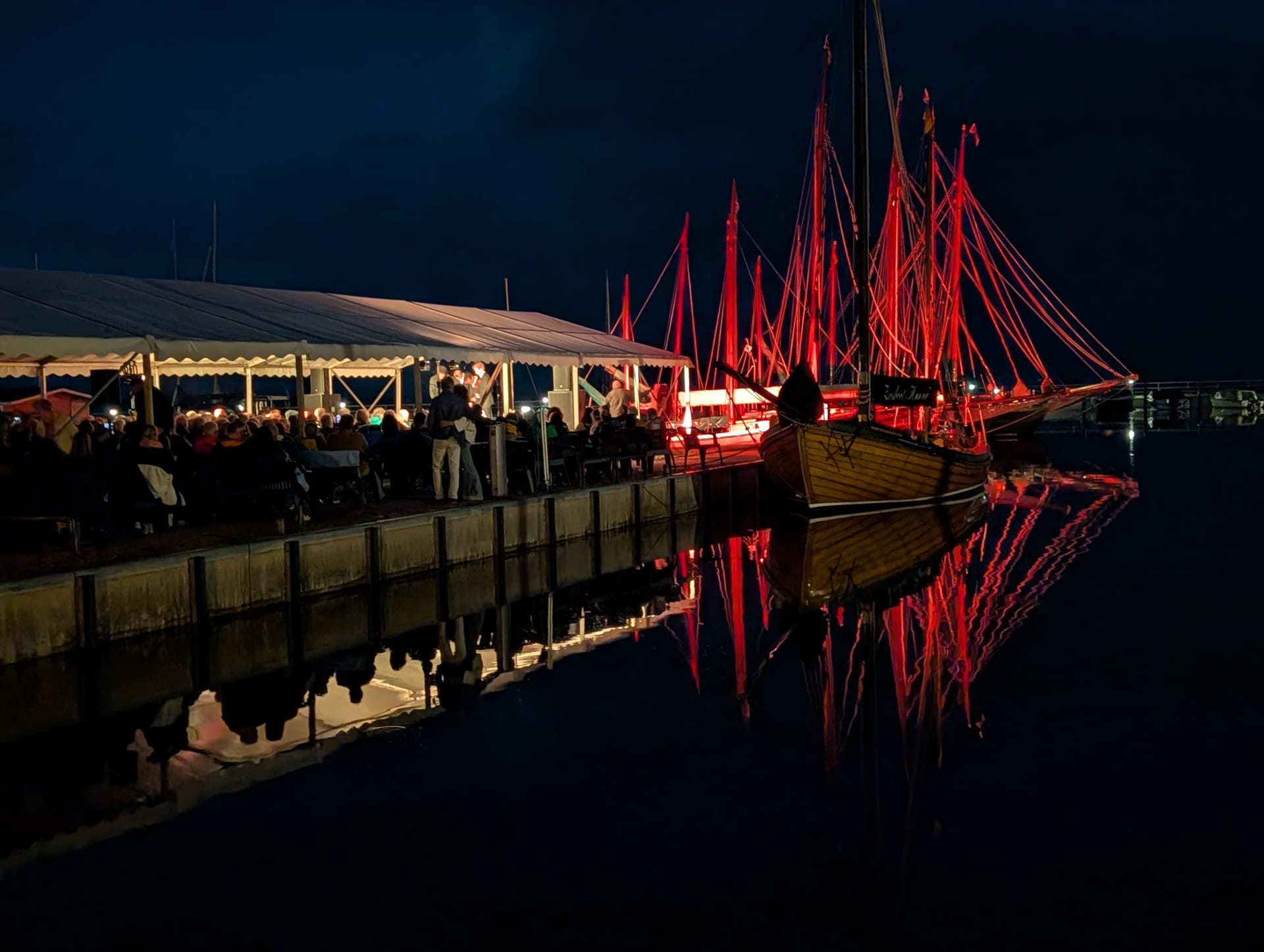 Abendveranstaltung am Hafen mit rot beleuchteten Masten