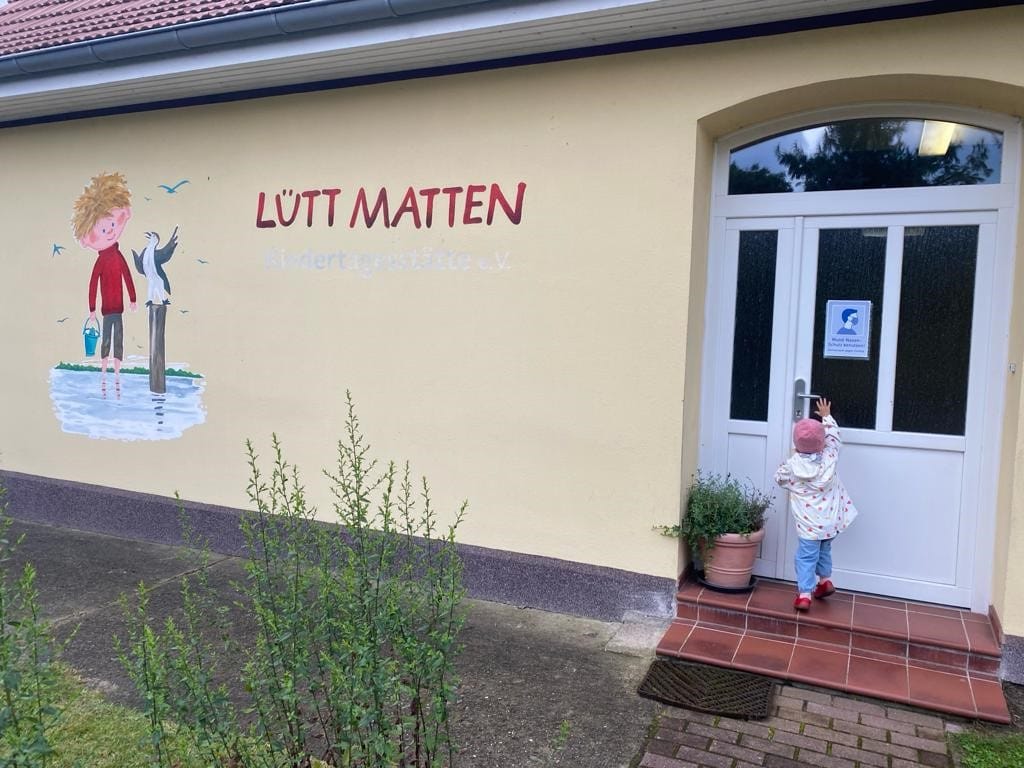Kind steht vor Tür des Kindergarten Lütt Matten