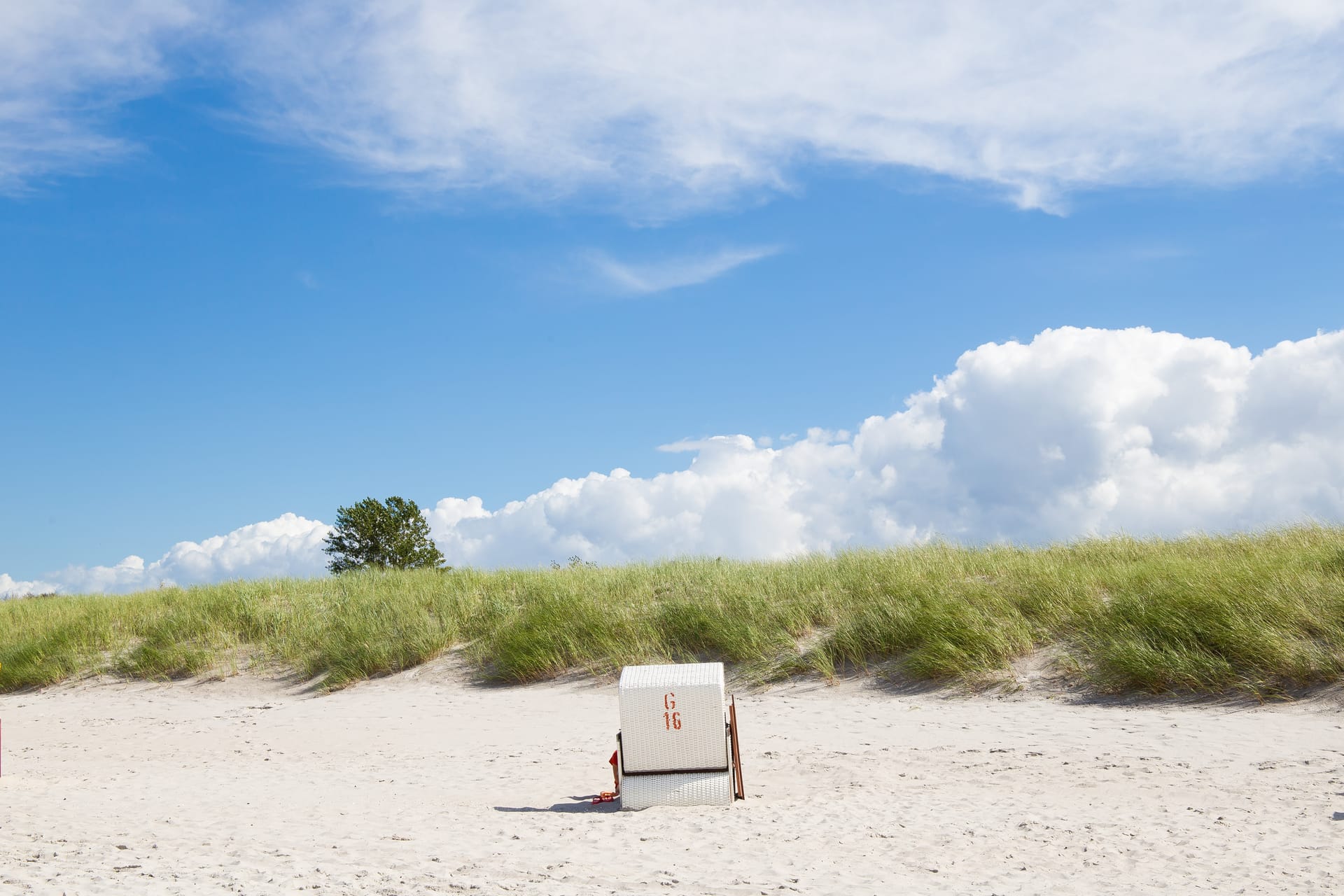 Strandkorb am Ostseestrand mit Dünen und blauem Himmel