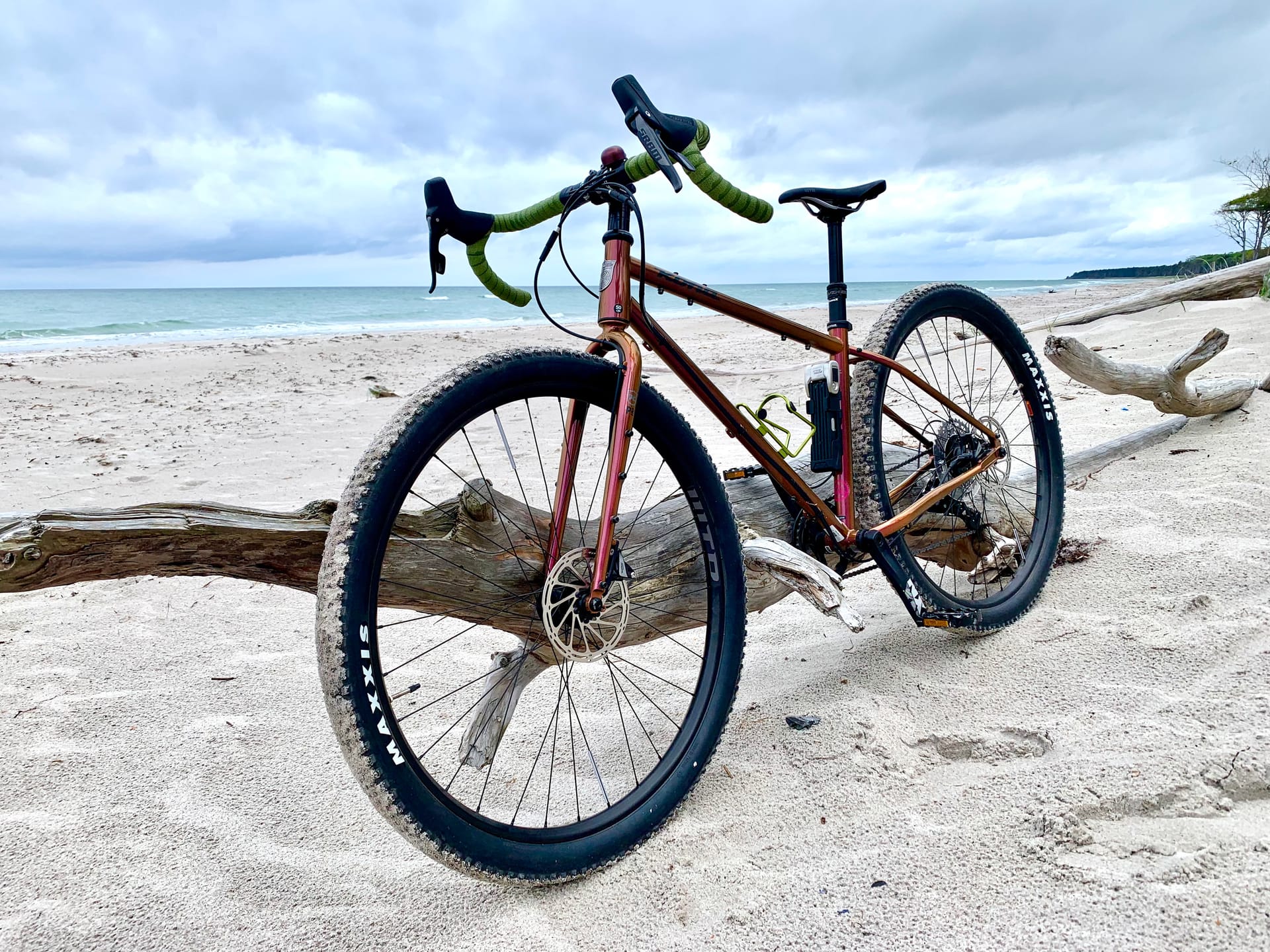 Fahrrad steht am Strand an einen Baumstamm gelehnt