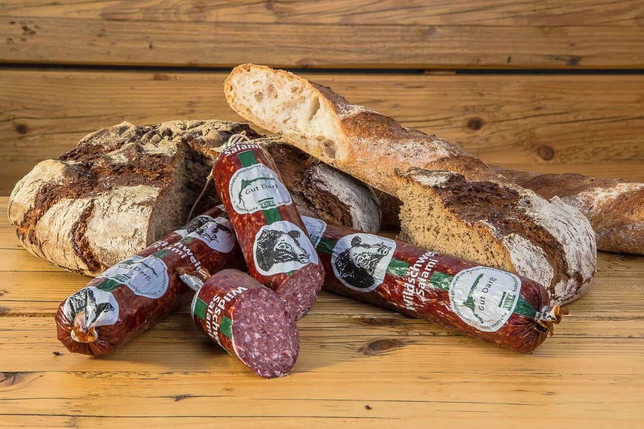 Wildschweinsalami mit rustikalem Brot auf Holztisch angerichtet
