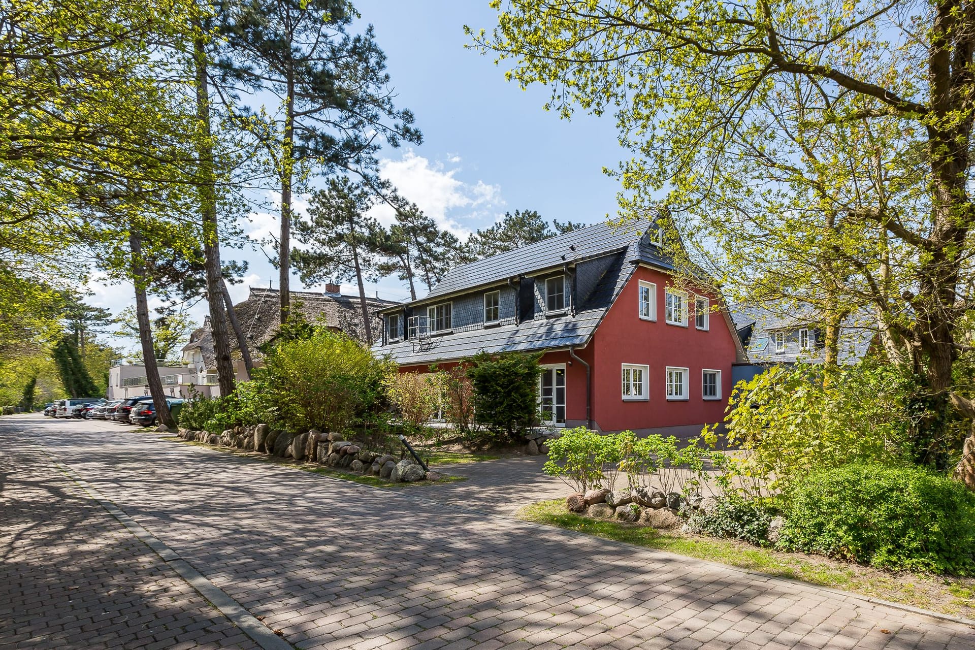 Außenansicht eines roten Hauses mit grünem Garten.