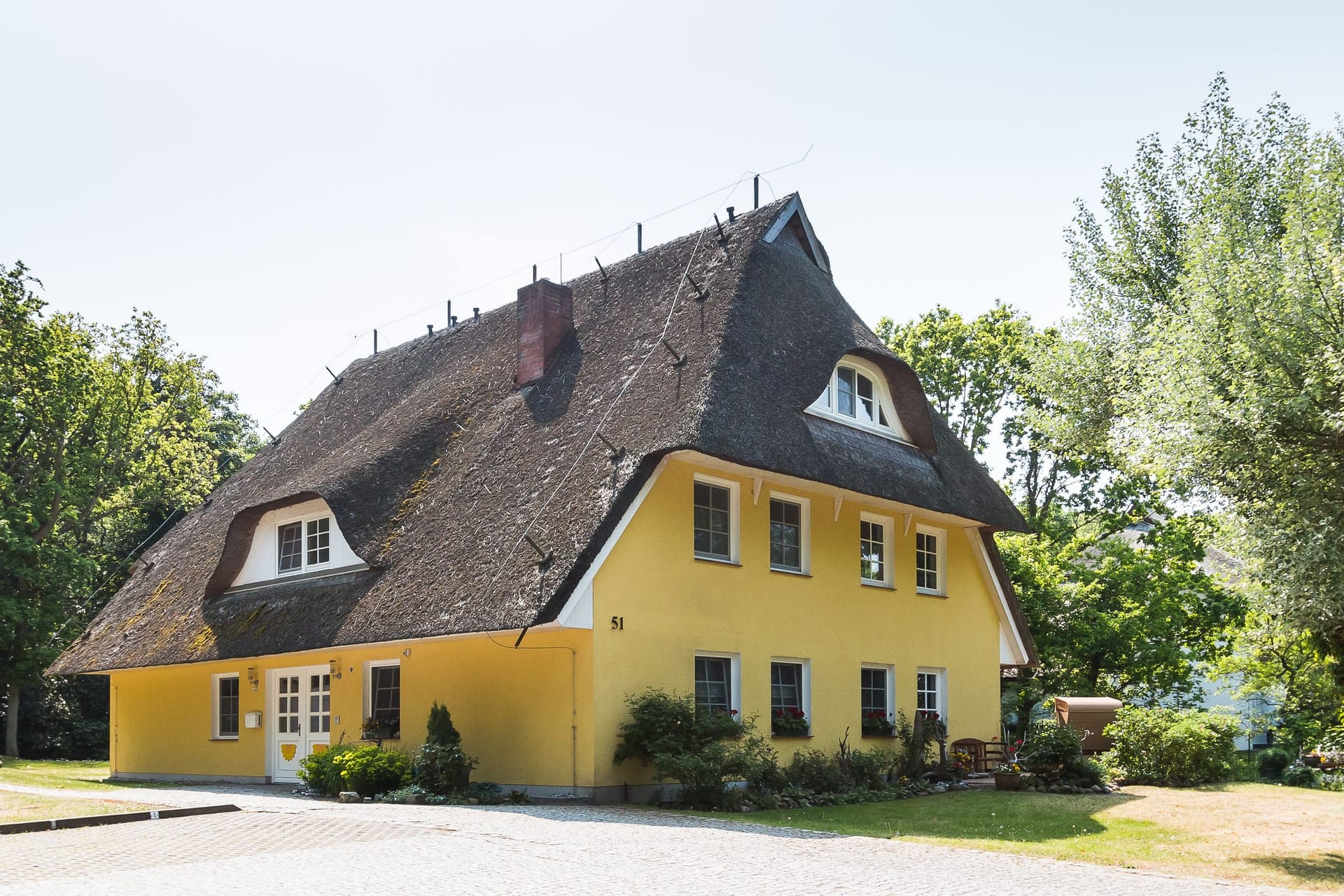 Außenansicht eines gelben Hauses mit Reetdach