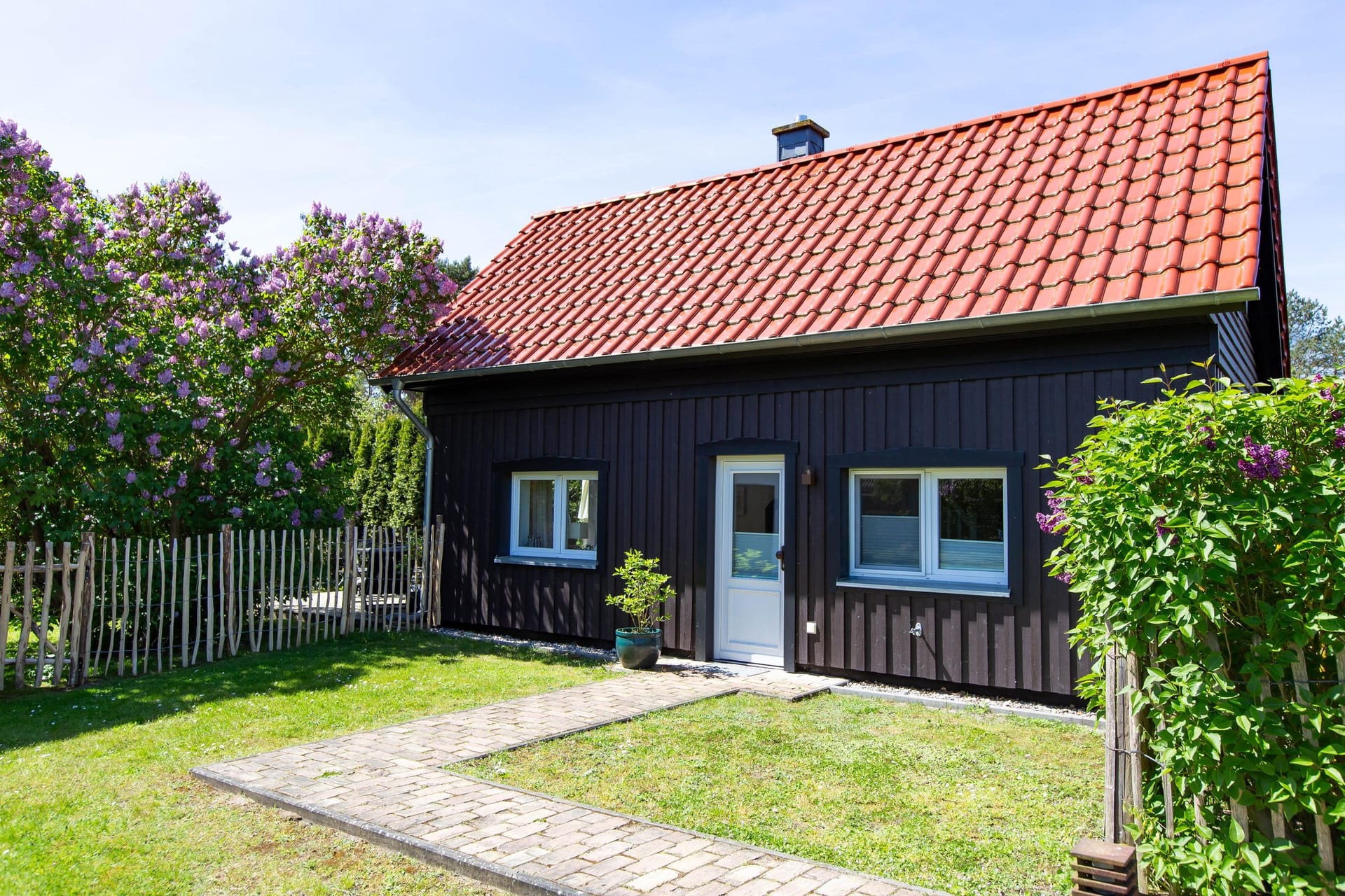 Außenansicht eines schwarzen Hauses mit rotem Dach