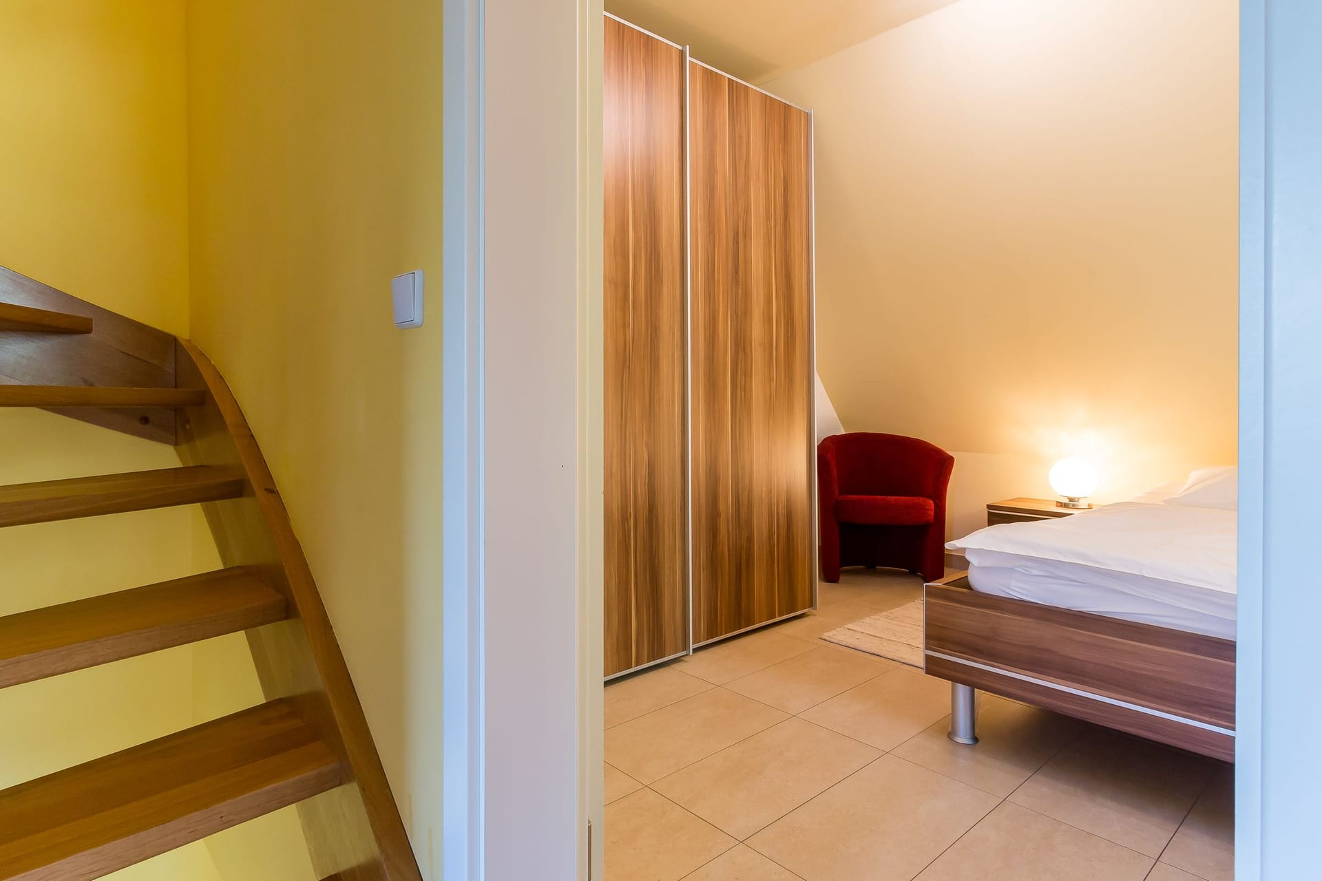 Schlafzimmer mit Bett und rotem Sessel