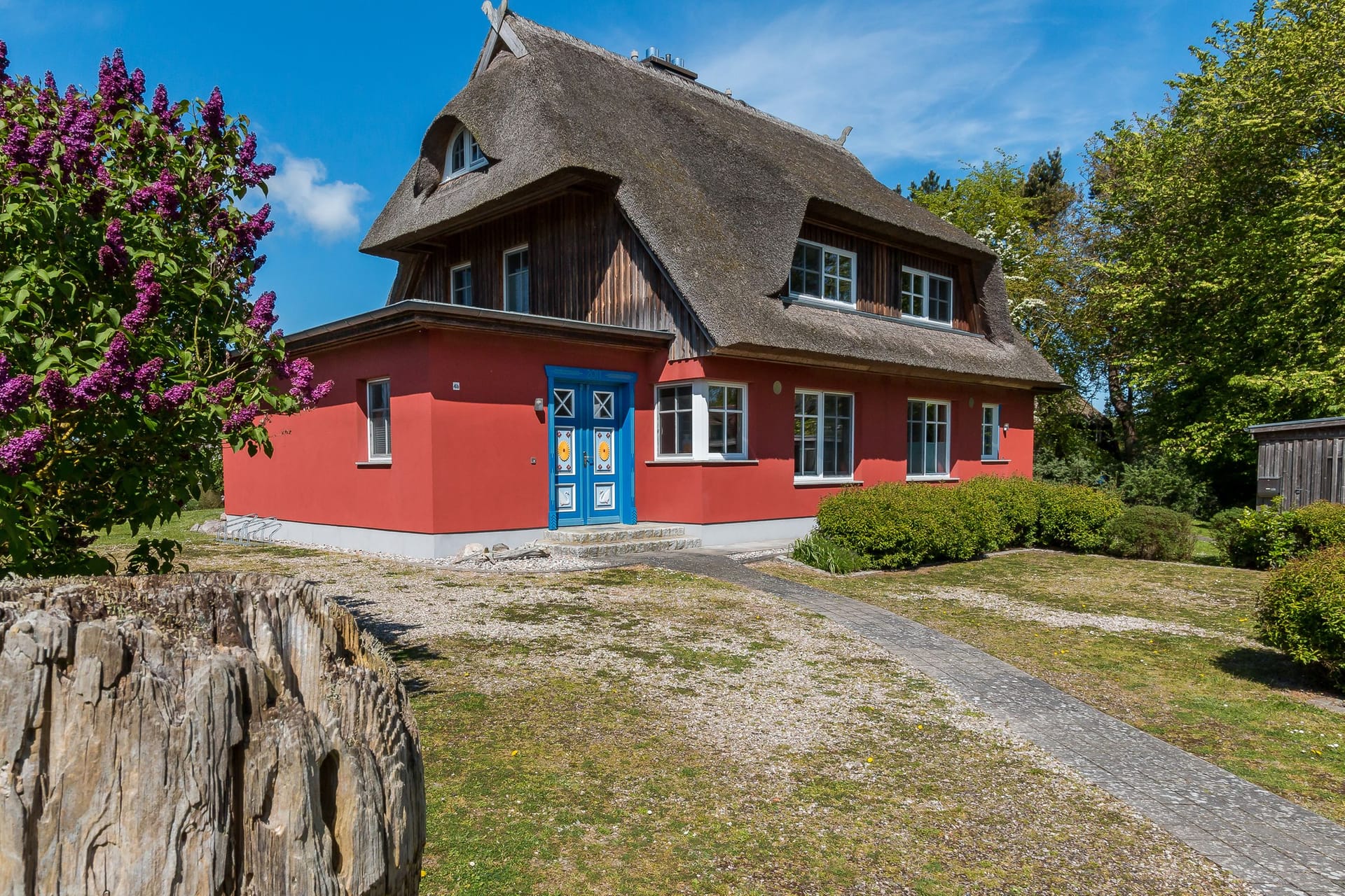 Einfamilienhaus mit roter Fassade und Strohdach