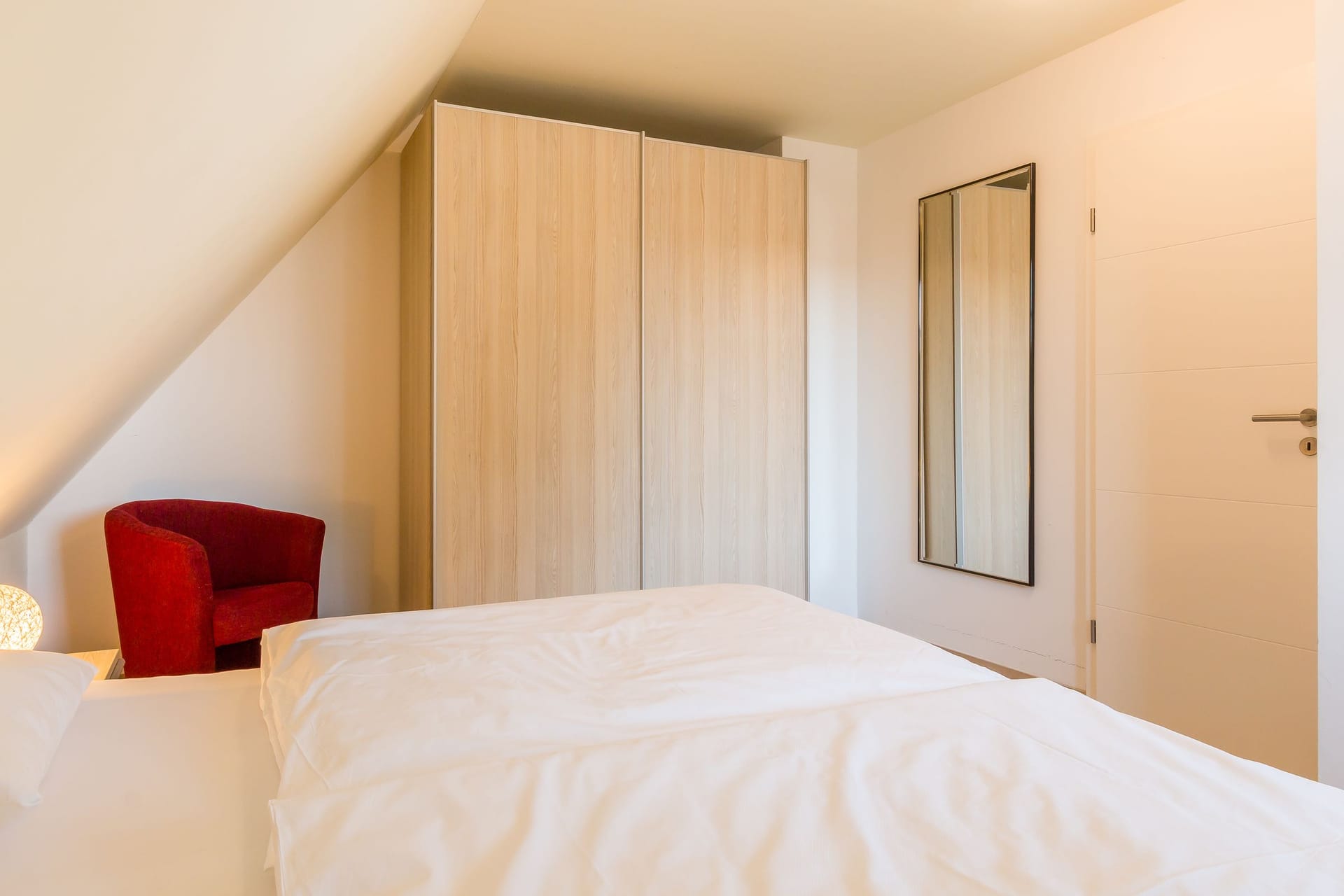 Schlafzimmer mit Doppelbett und rotem Sessel