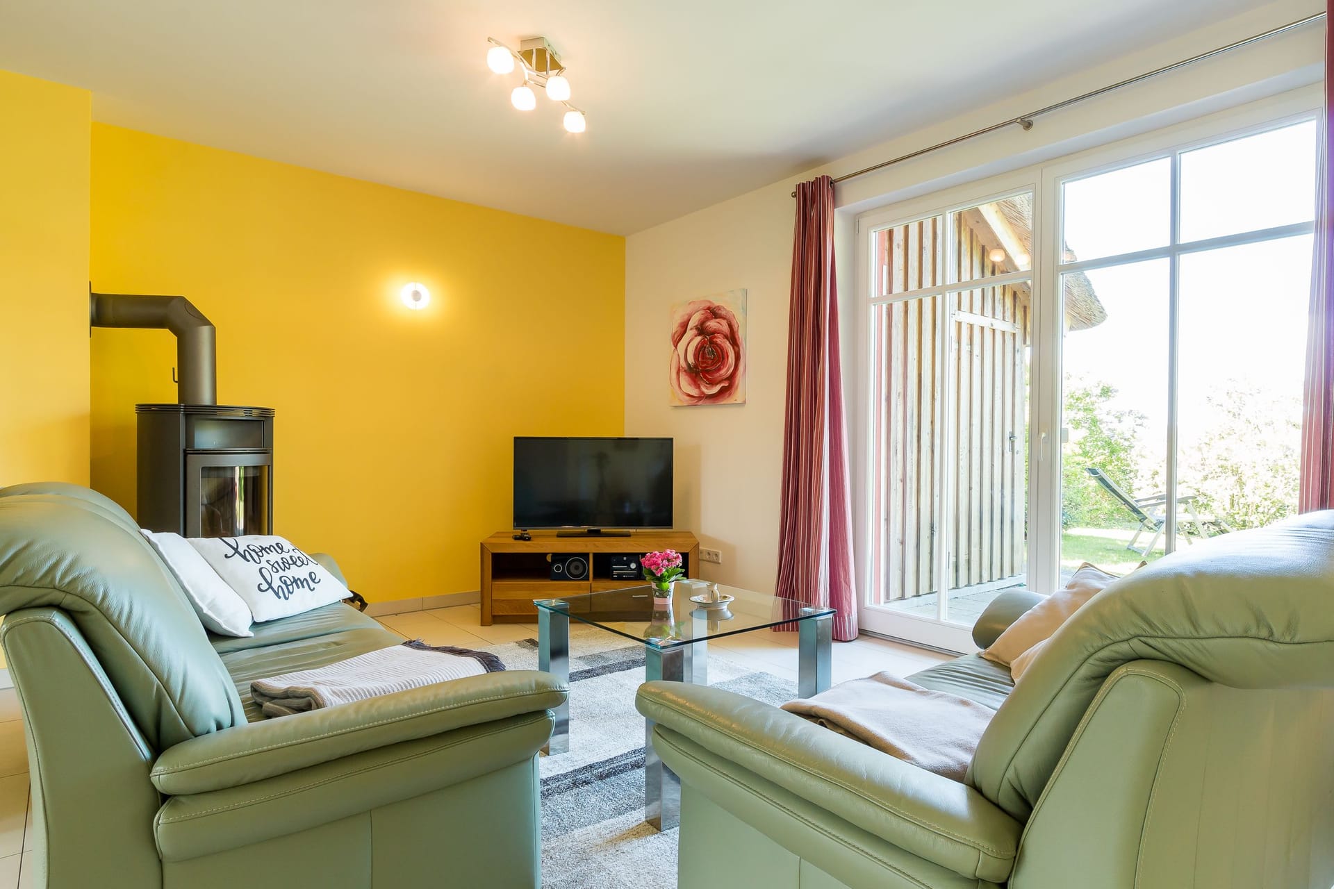 Gemütliches Wohnzimmer mit Fernseher und Ausblick nach draußen.