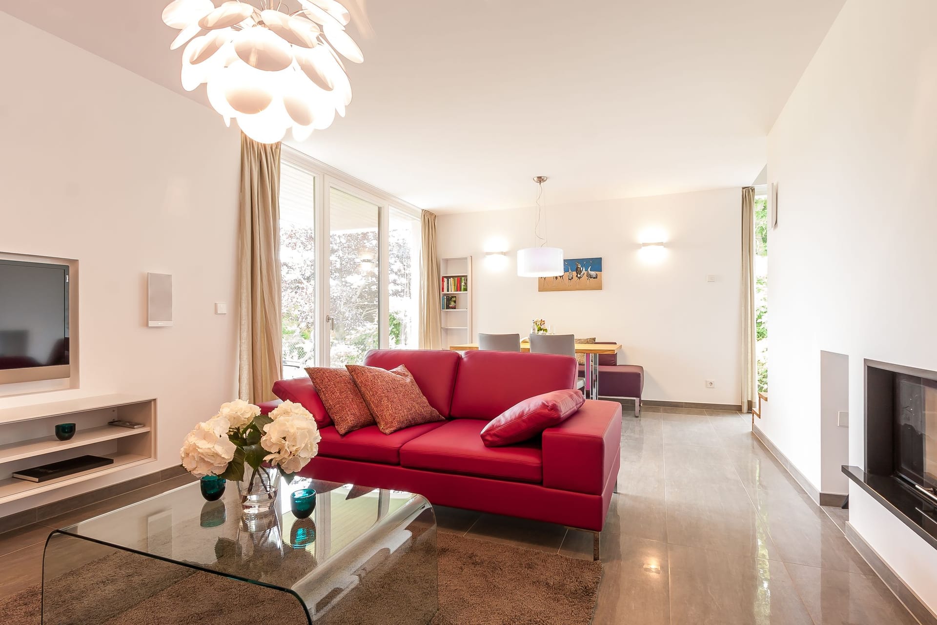 Helles Wohnzimmer mit rotem Sofa und Glas-Tisch