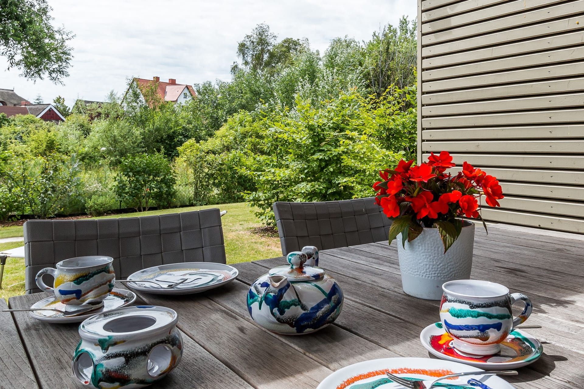 Terrasse mit Tisch, Geschirr und blühenden Pflanzen