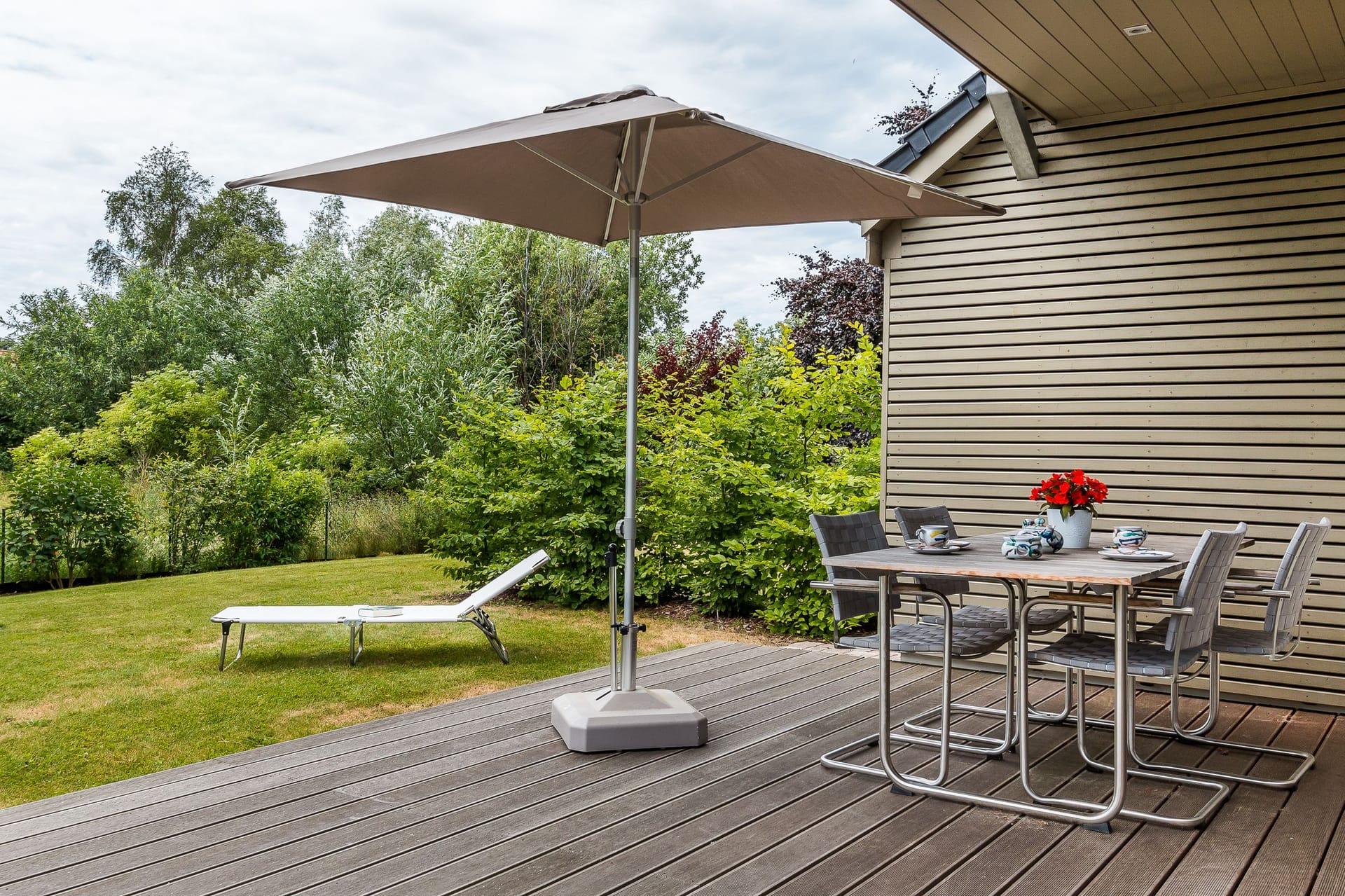 Terrasse mit Tisch, Stühlen und Sonnenschirm.