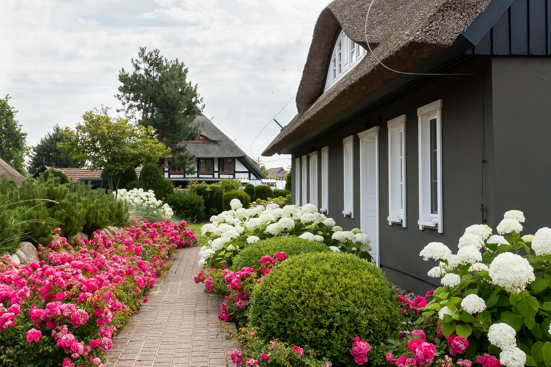 Außenansicht eines Hauses mit bunten Blumenbeeten