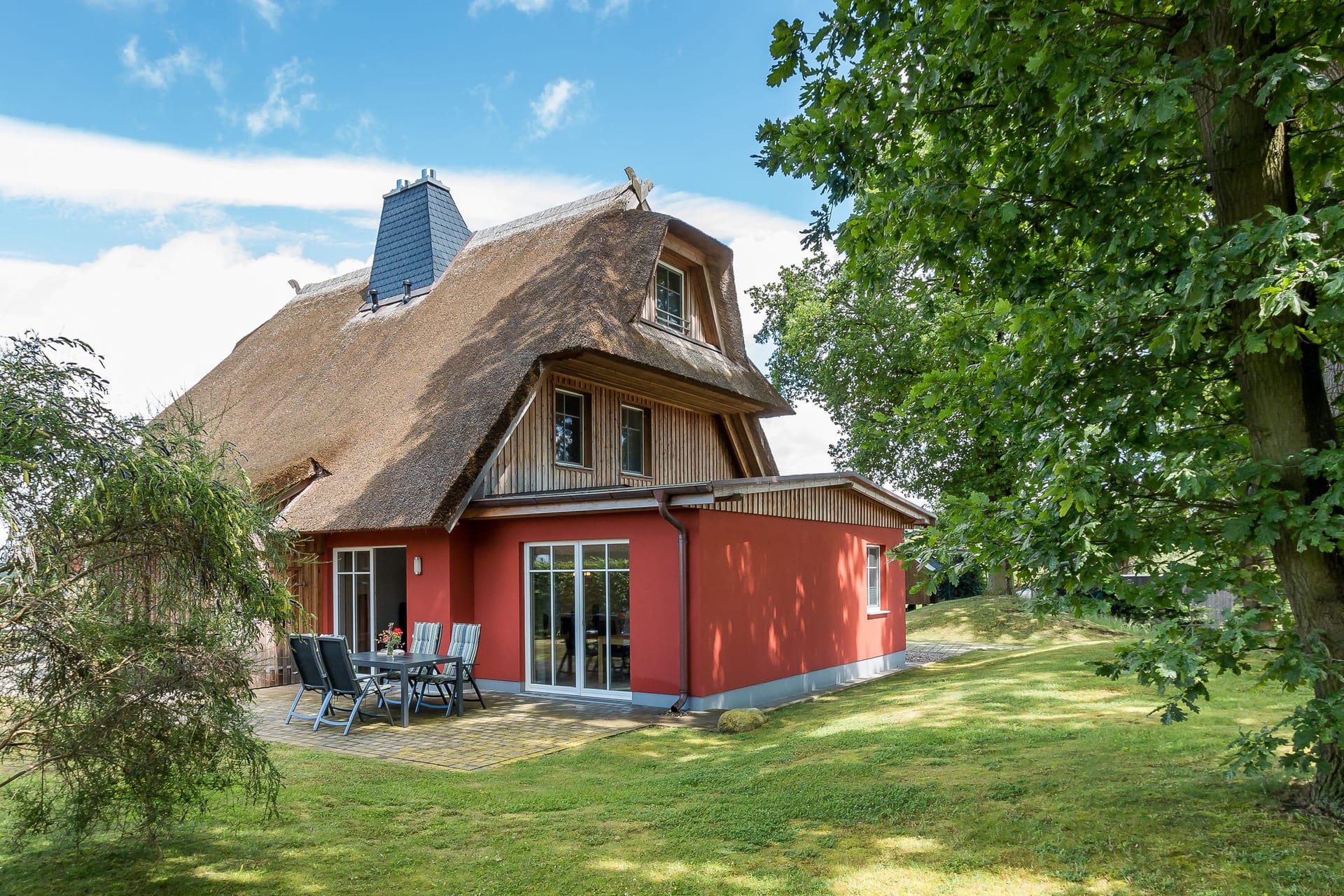 Außenansicht eines Reetdachhauses mit Terrasse