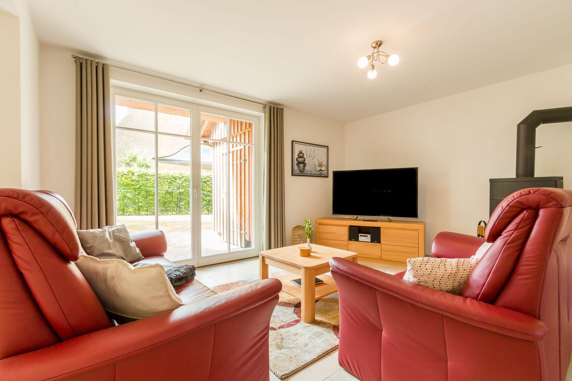Helles Wohnzimmer mit roten Sesseln und Fernseher