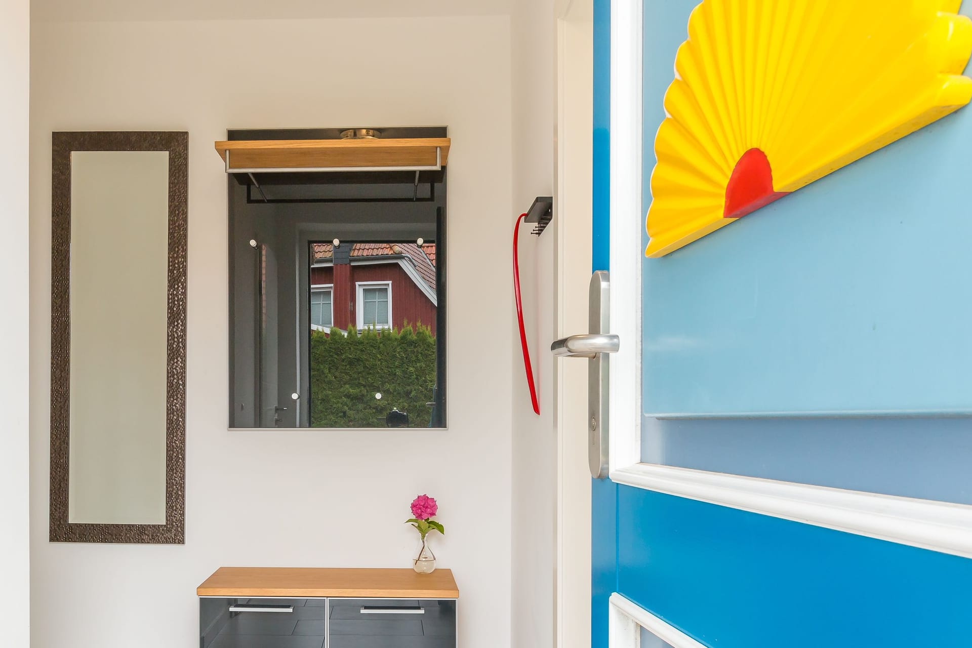 Eingangsbereich mit modernem Spiegel und Holzablage.