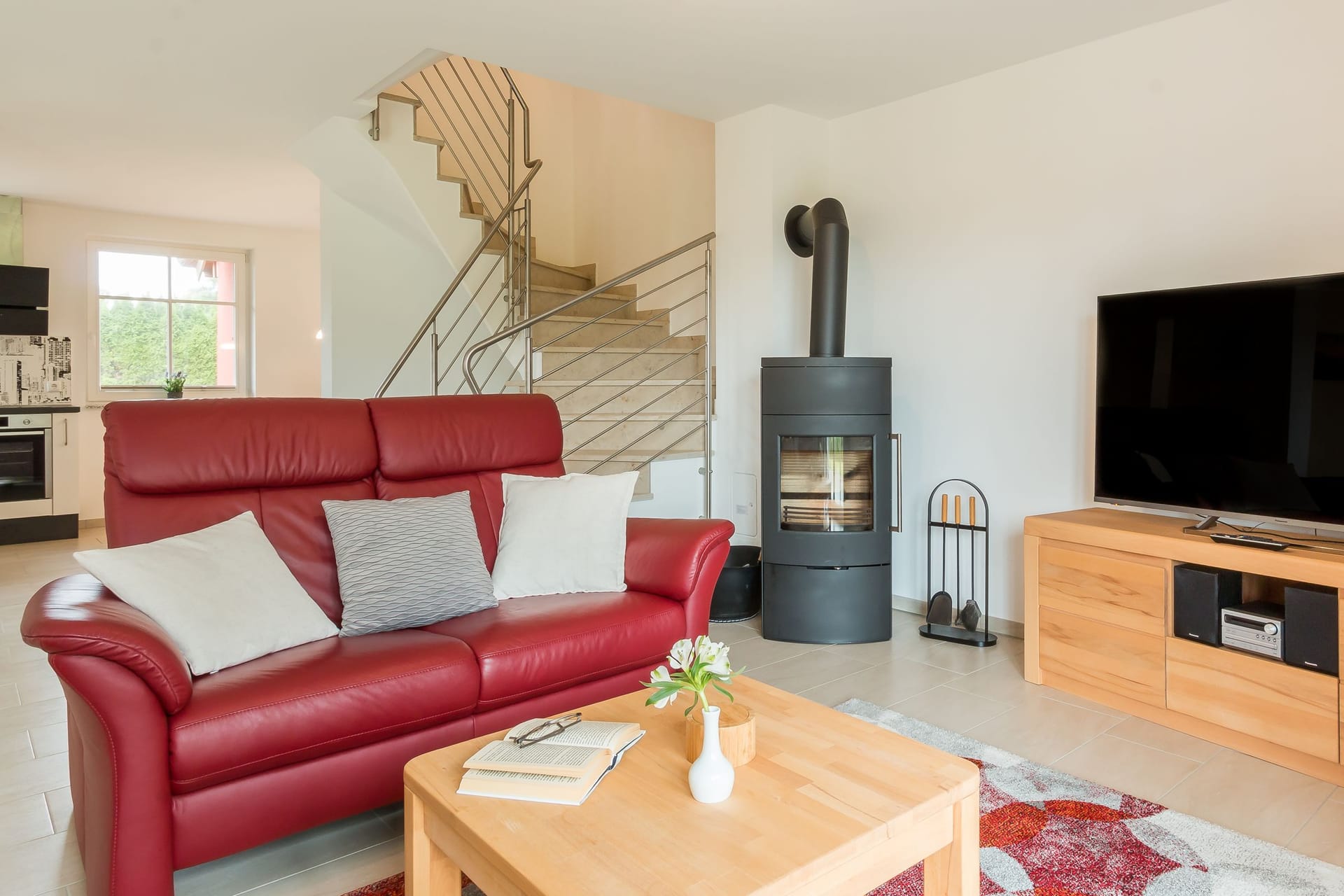 Geräumiges Wohnzimmer mit rotem Sofa und Fernseher.