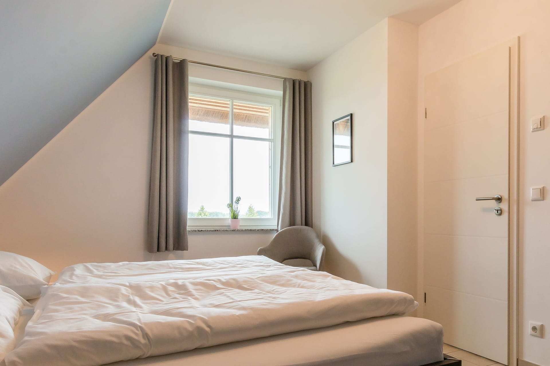 Helles Schlafzimmer mit Doppelbett und großem Fenster