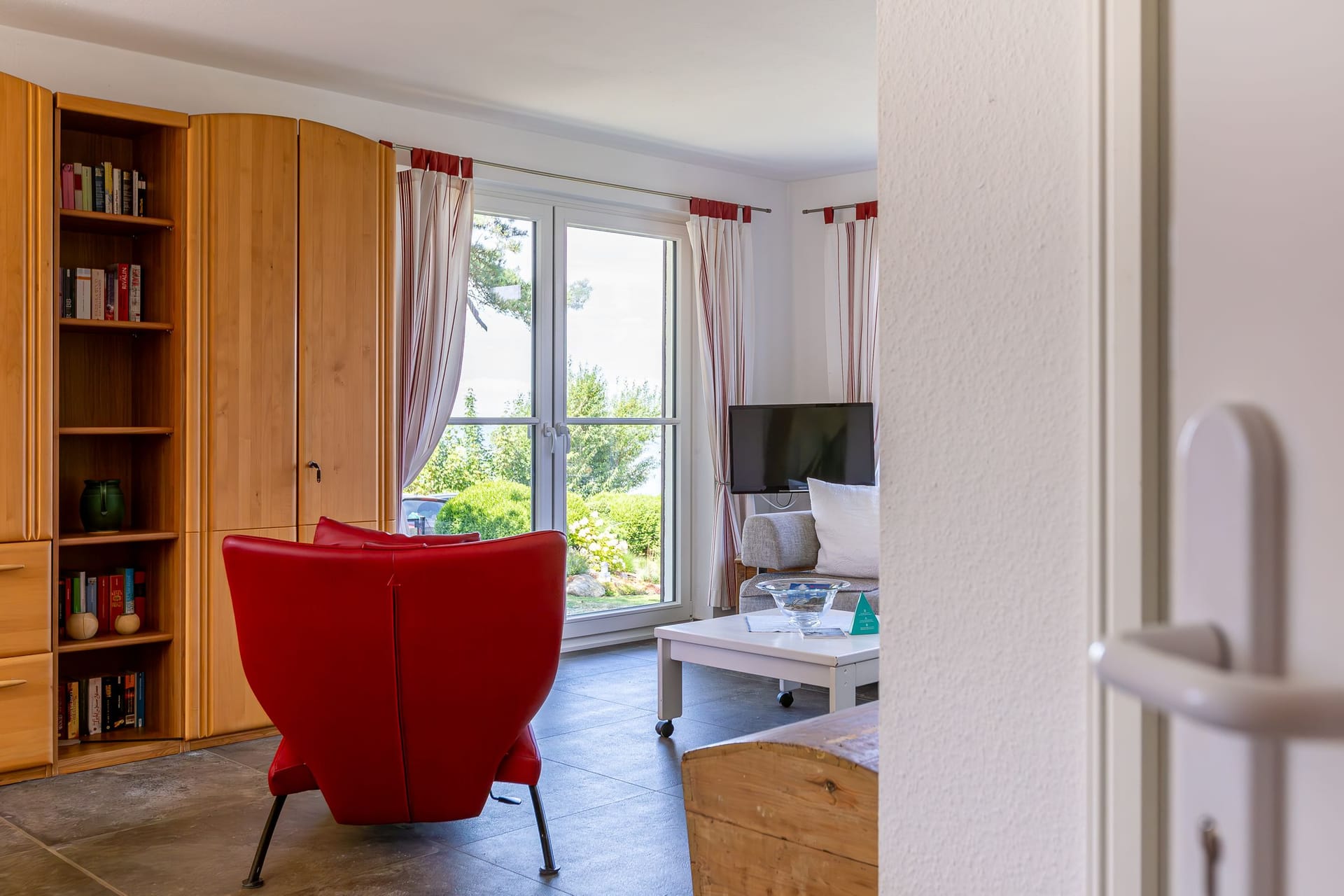 Gemütliches Wohnzimmer mit rotem Sessel und Fernseher