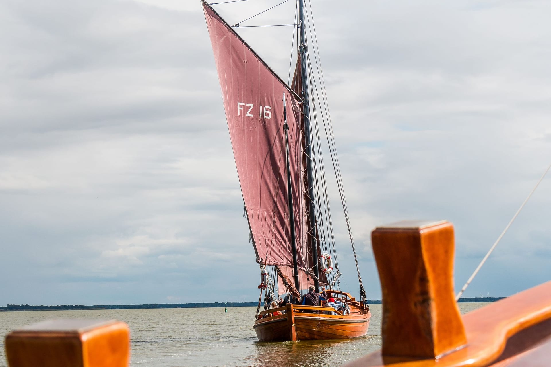 Segelboot auf ruhigem Wasser mit roten Segeln