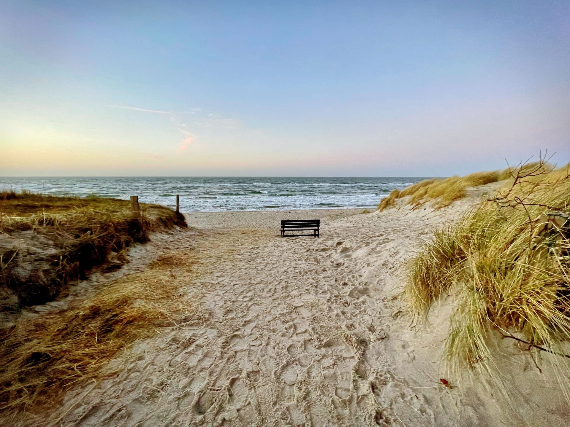 Strand mit Holzbank und sanften Dünen