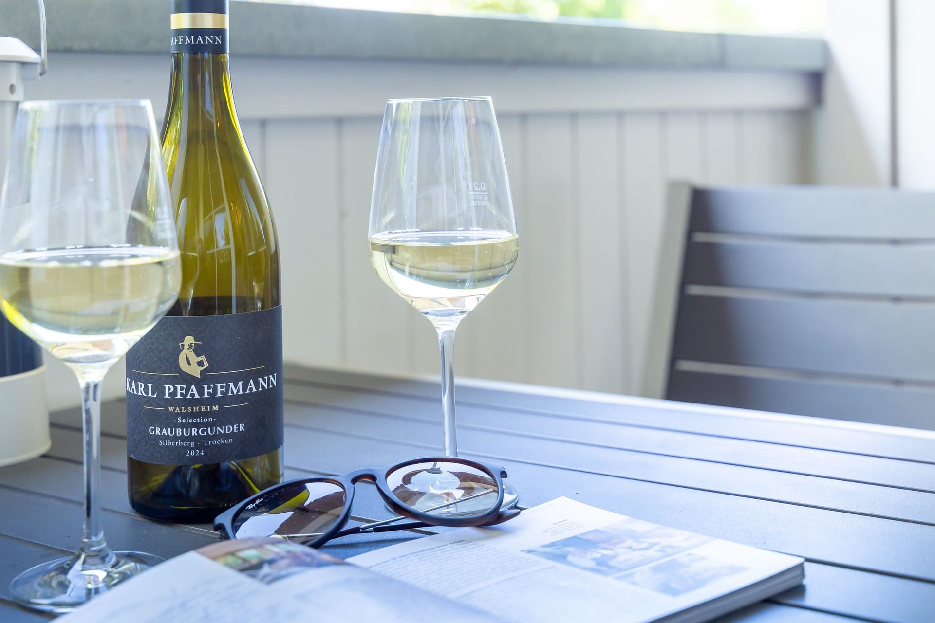 Terrasse mit Weingläsern und einer Flasche Wein