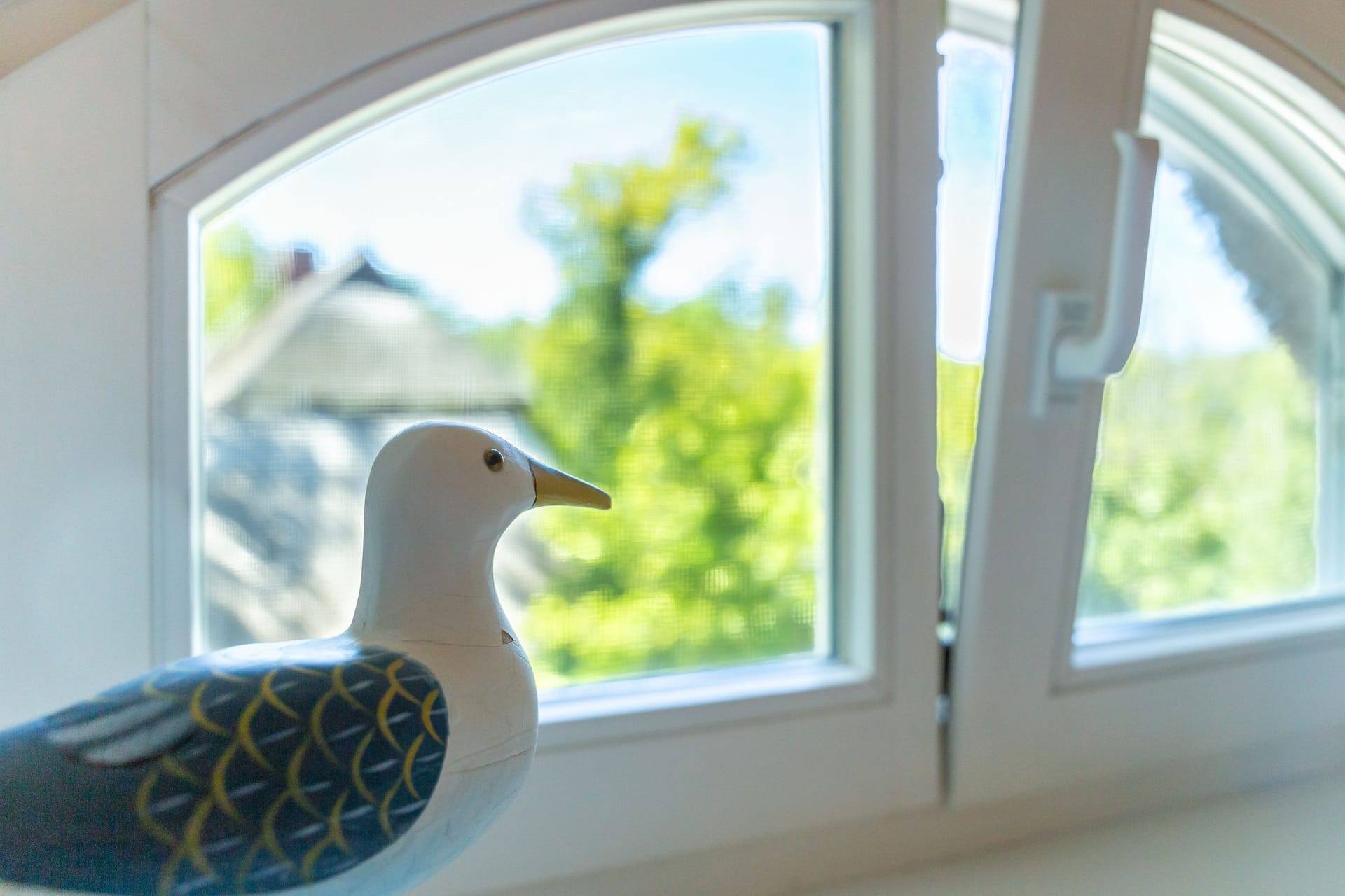 Fenster mit Blick auf Bäume und Vogelfigur