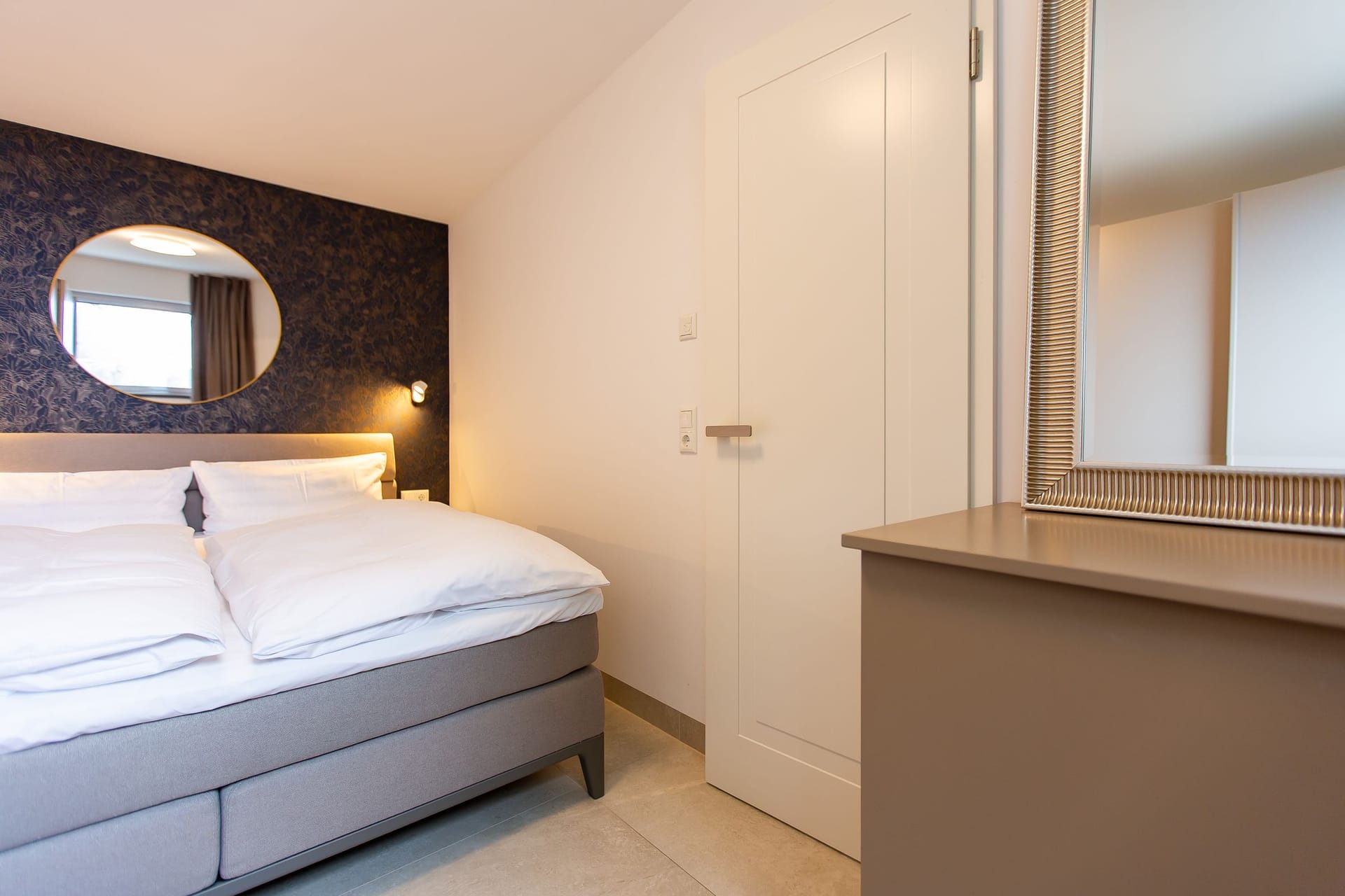 Schlafzimmer mit Doppelbett und modernem Spiegel