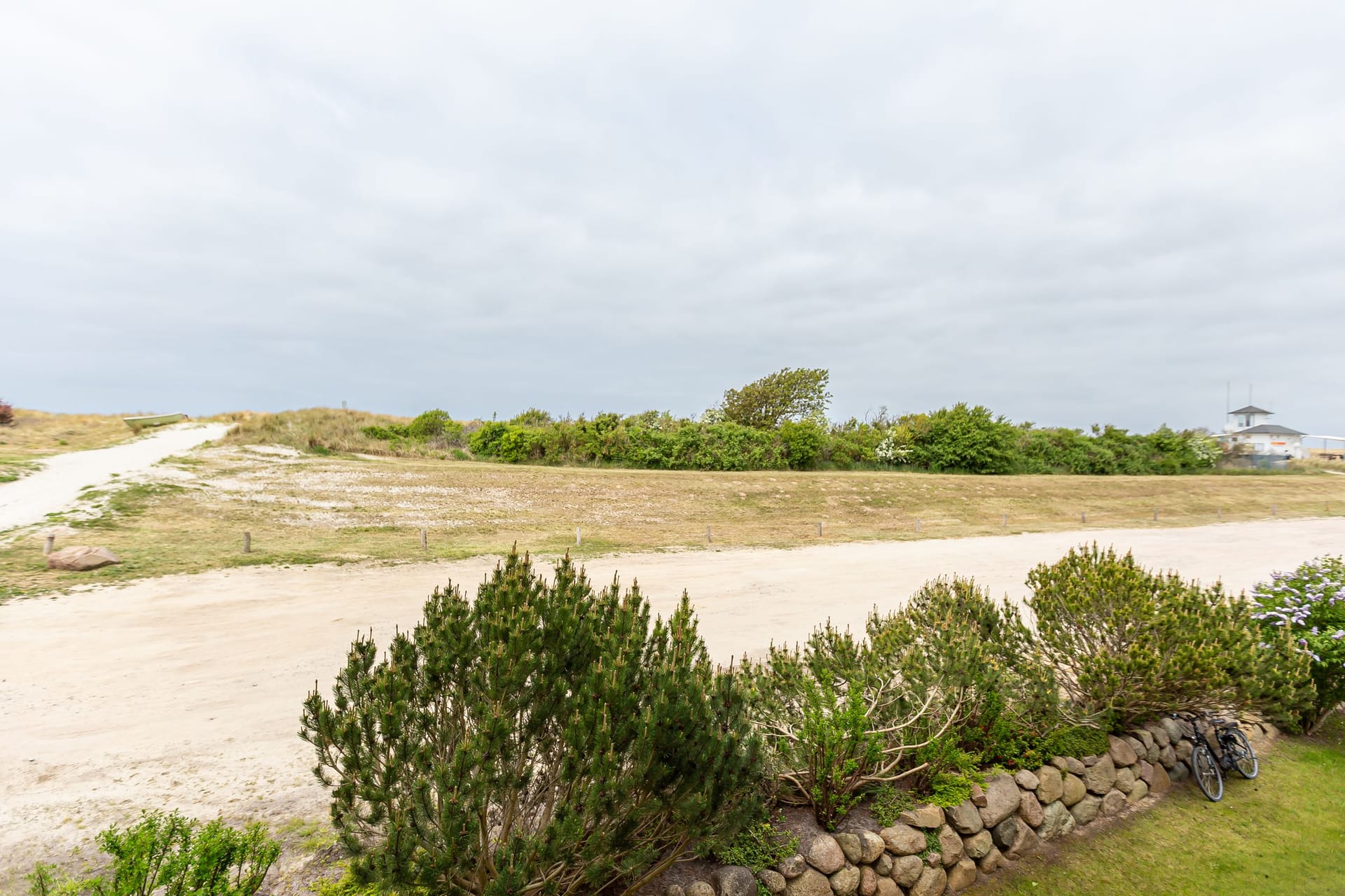 Strandansicht mit sandigem Weg und Vegetation