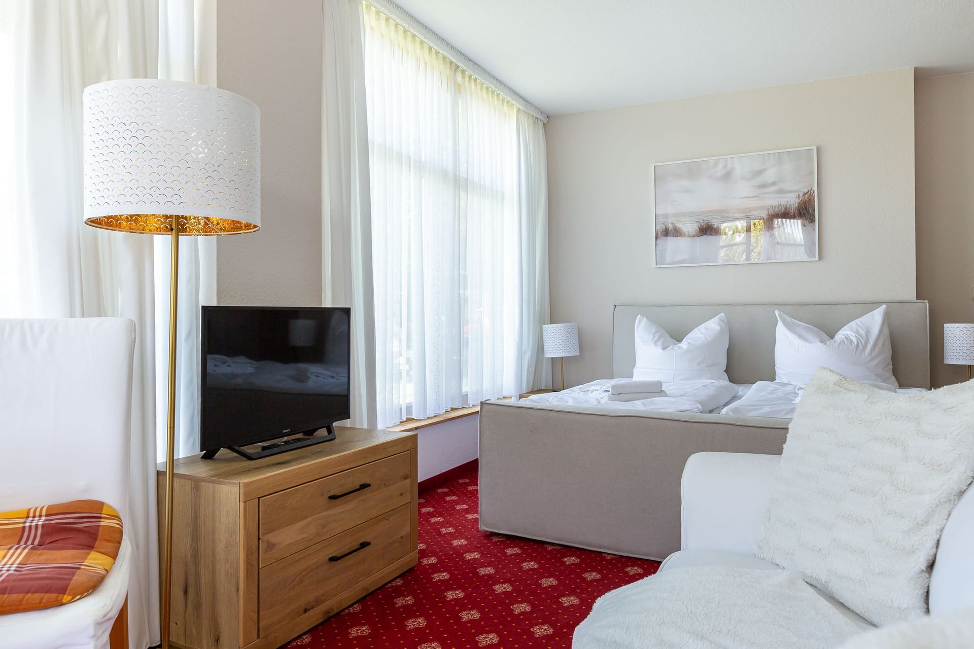 Helles Schlafzimmer mit Doppelbett und TV