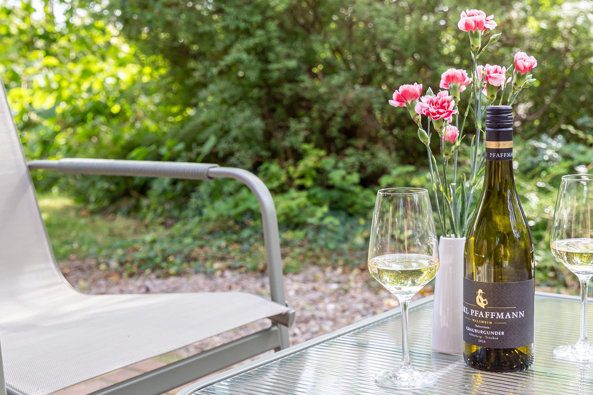 Terrasse mit Tisch, Stühlen und Weinflasche