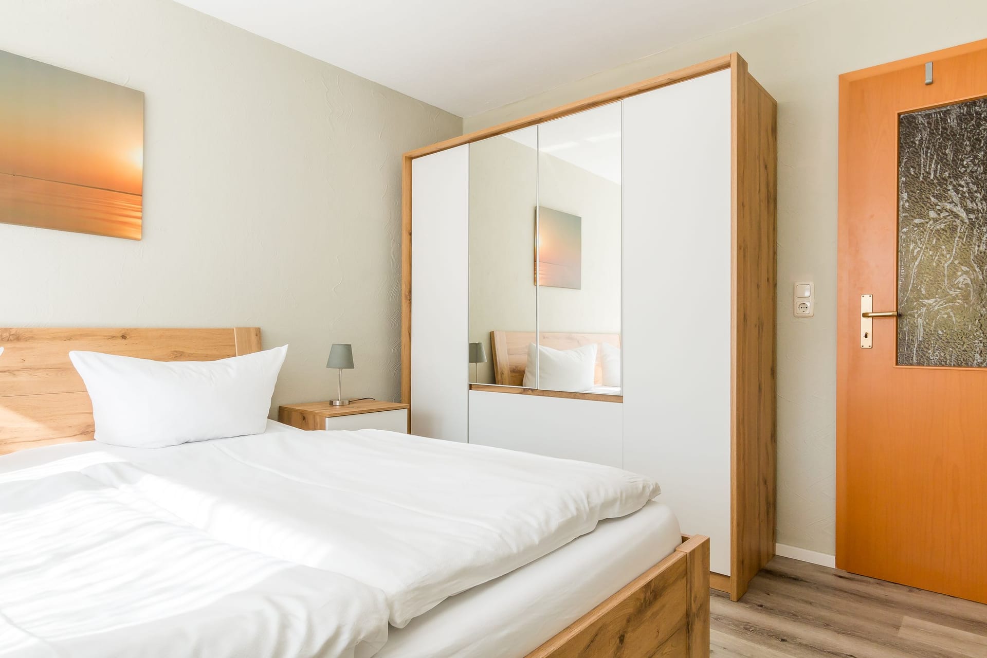 Helles Schlafzimmer mit kleinem Nachttisch und Kleiderschrank