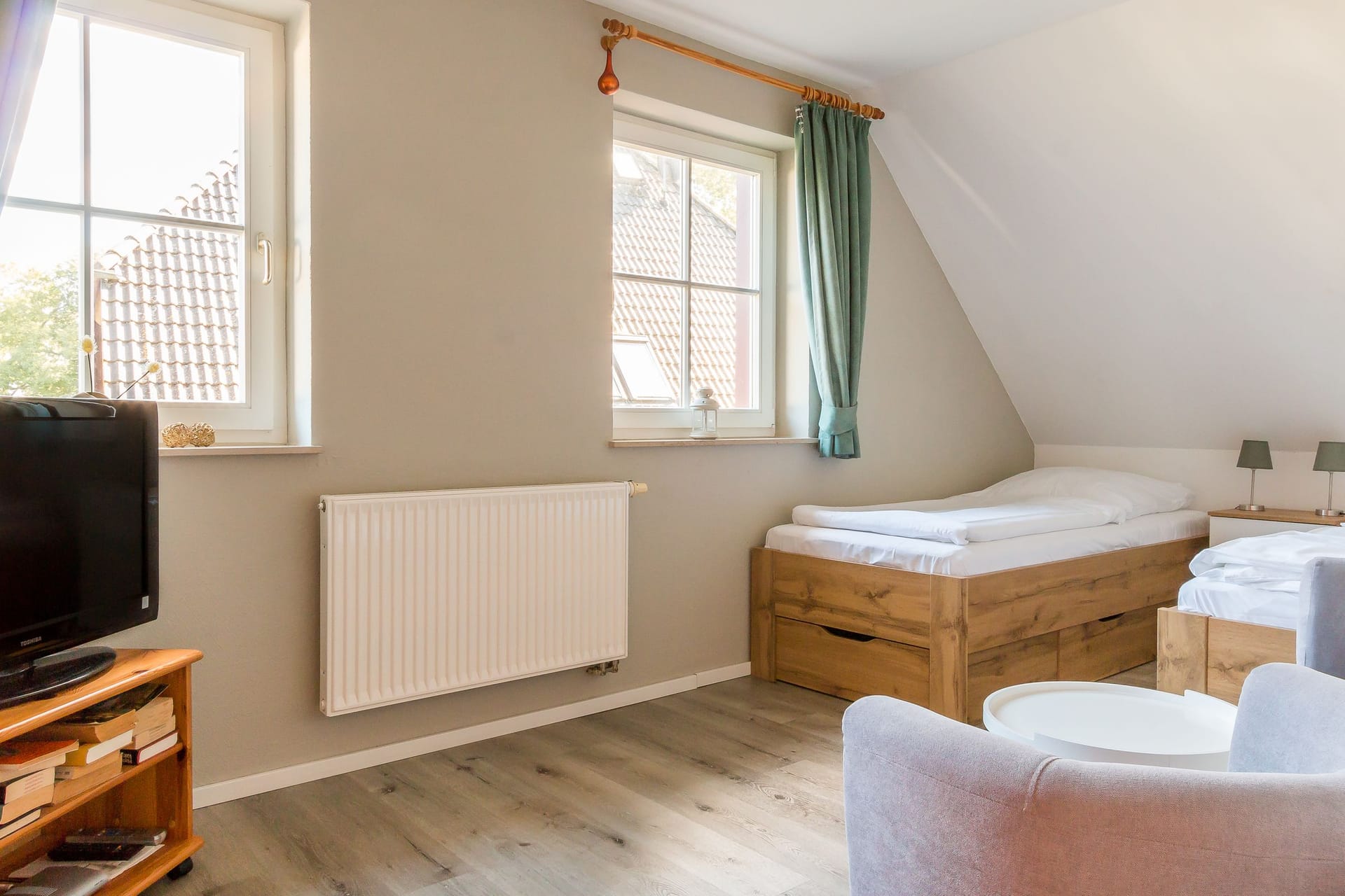 Helles Schlafzimmer mit Holzbetten und Fernseher