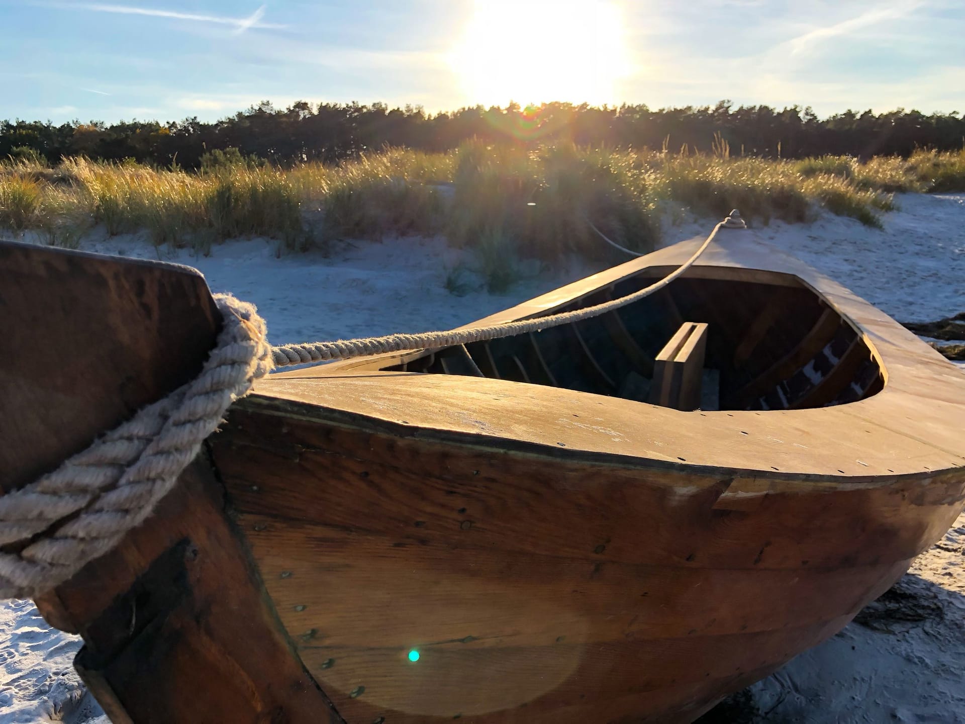 Holzboot am Strand bei Sonnenuntergang