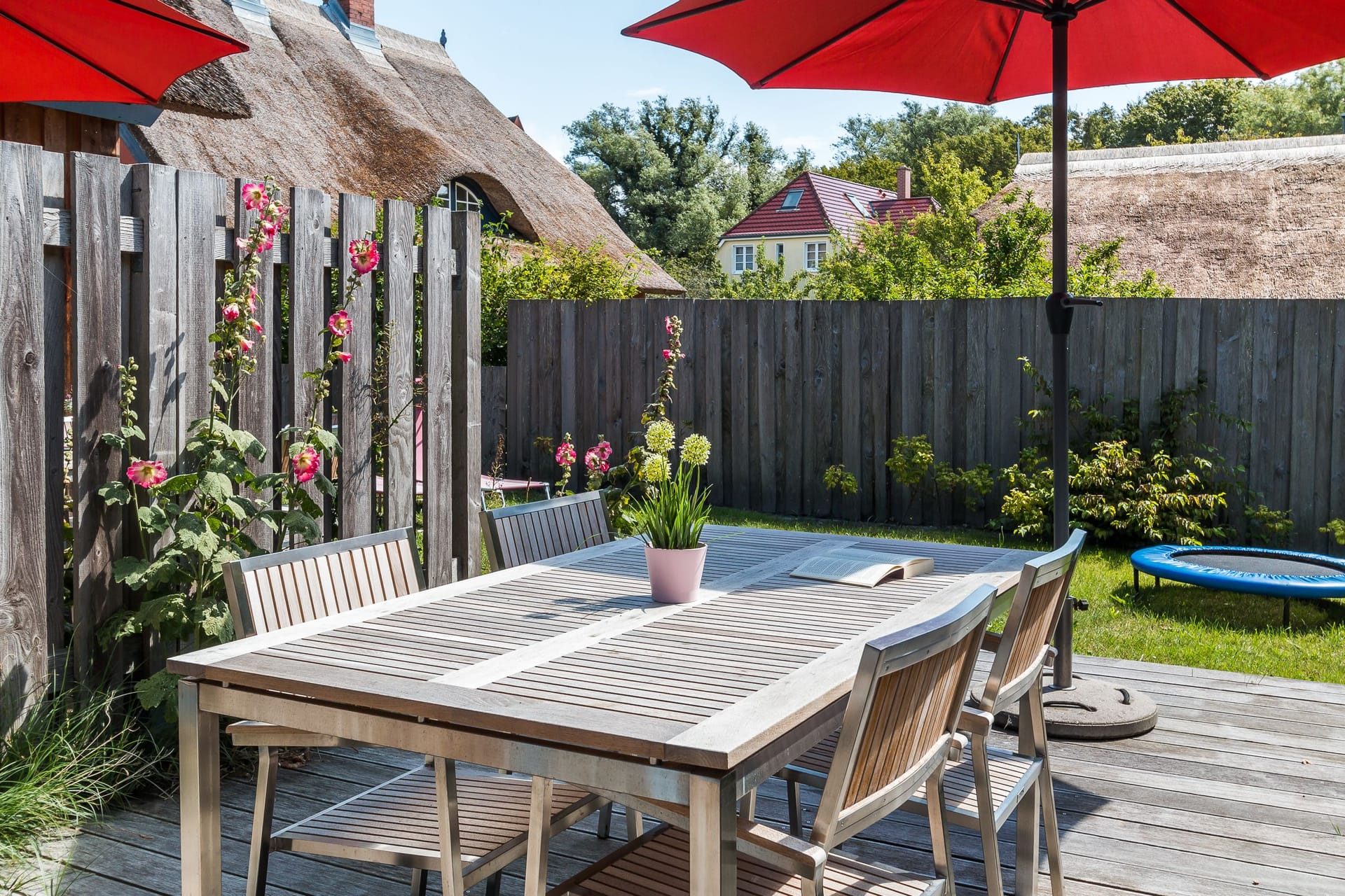 Terrasse mit Tisch und roten Sonnenschirmen